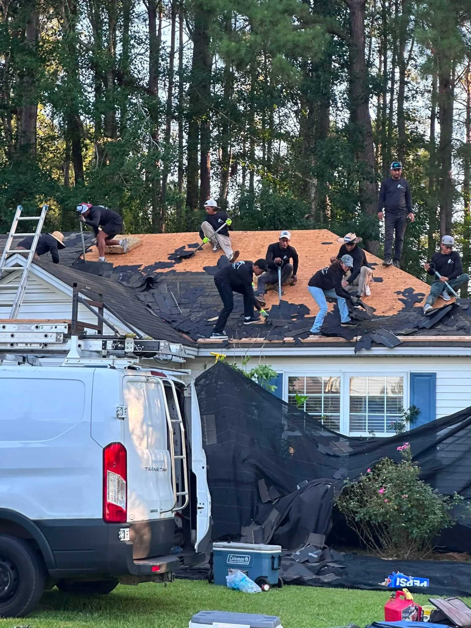 Roofing crew working on a residential shingle roof with tools and materials at the job site