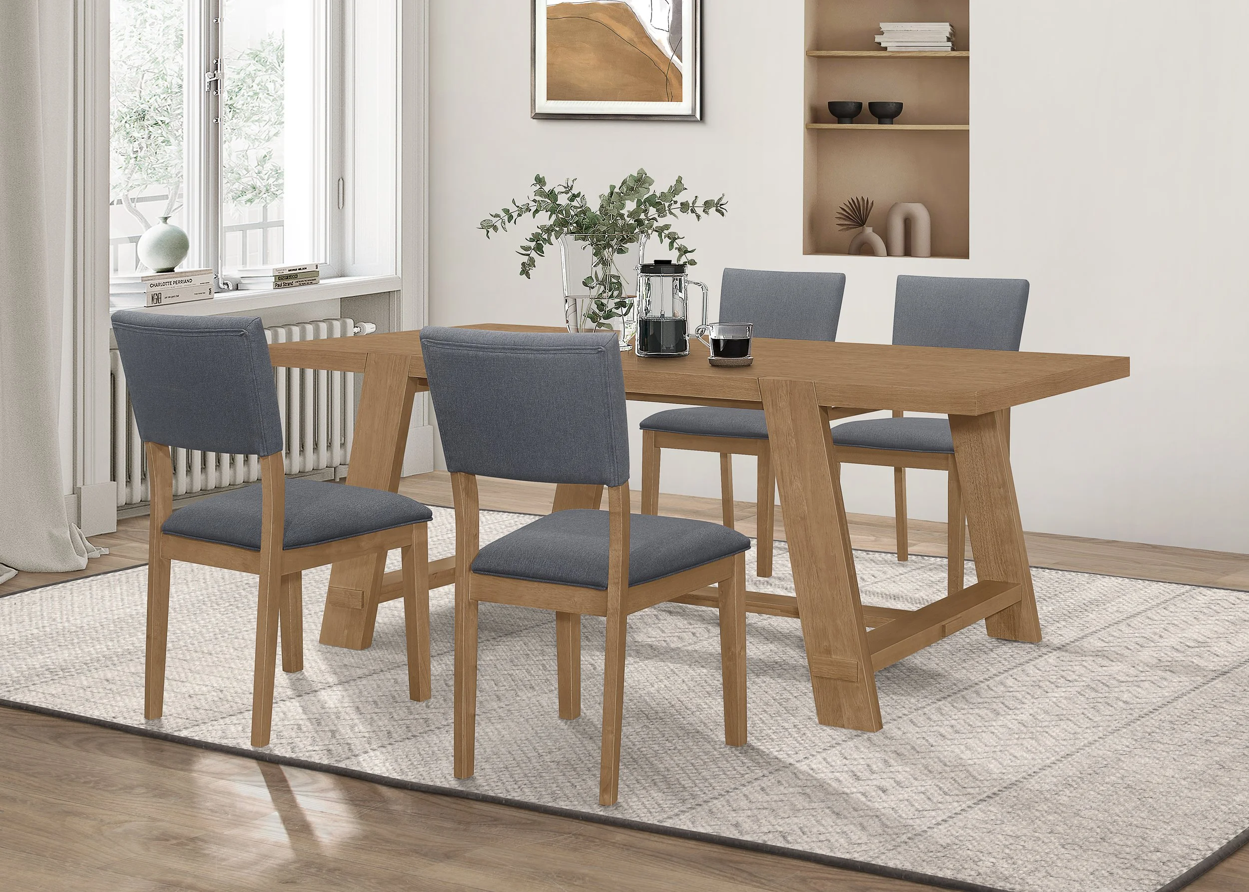 A dining room with a wooden table, four chairs with gray upholstered seats and backs, a window with white curtains, a beige wall with a piece of abstract art, a built-in shelf with decorative items, and a patterned area rug