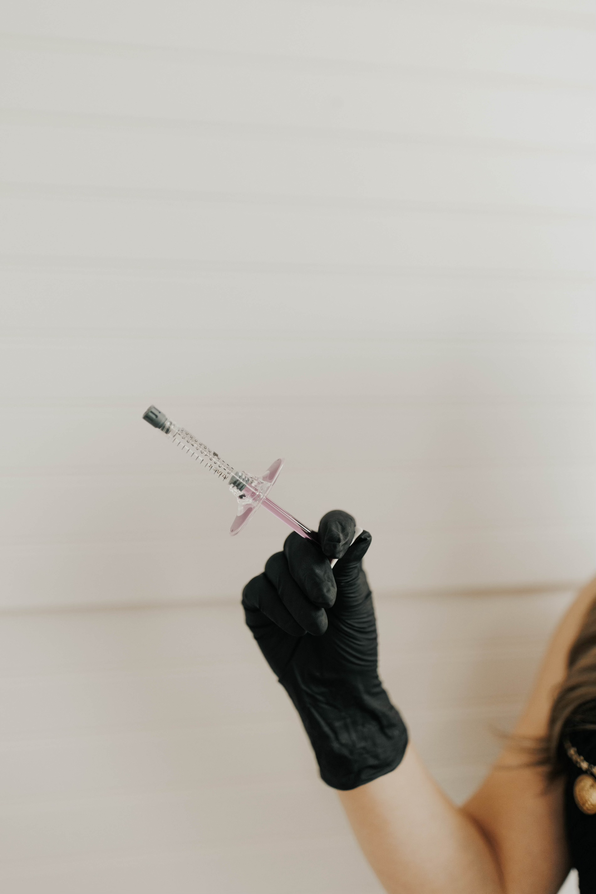 Aesthetic nurse practitioner at Golden Aesthetics holding a dermal filler syringe with black gloved hand
