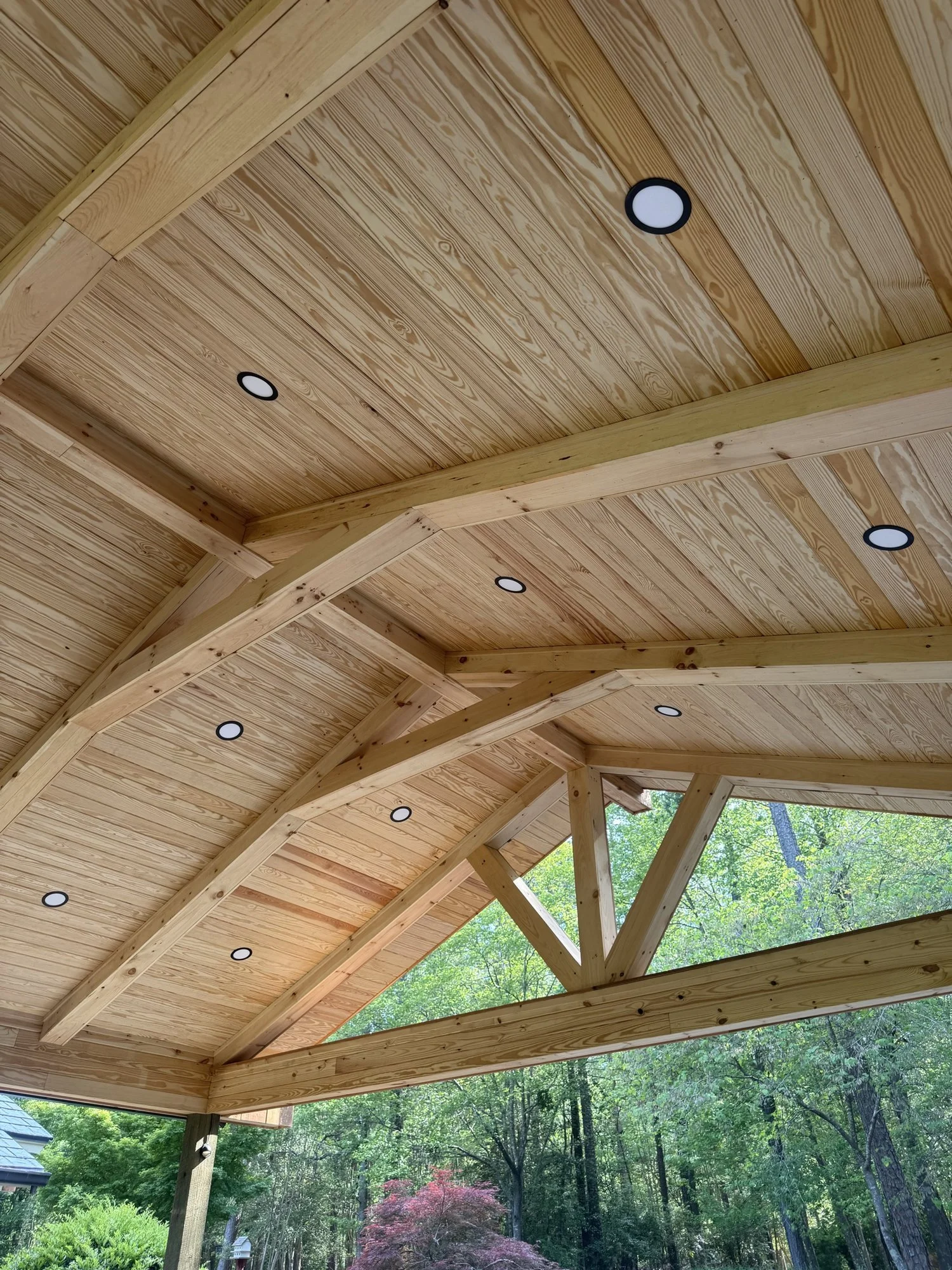 Pavilion ceiling detail: tongue-and-groove pine with recessed lighting under the timber trusses.