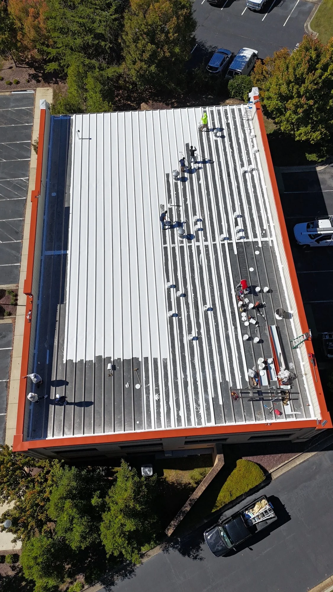 Commercial roofing in progress: coating being applied to the metal roof, one section at a time.