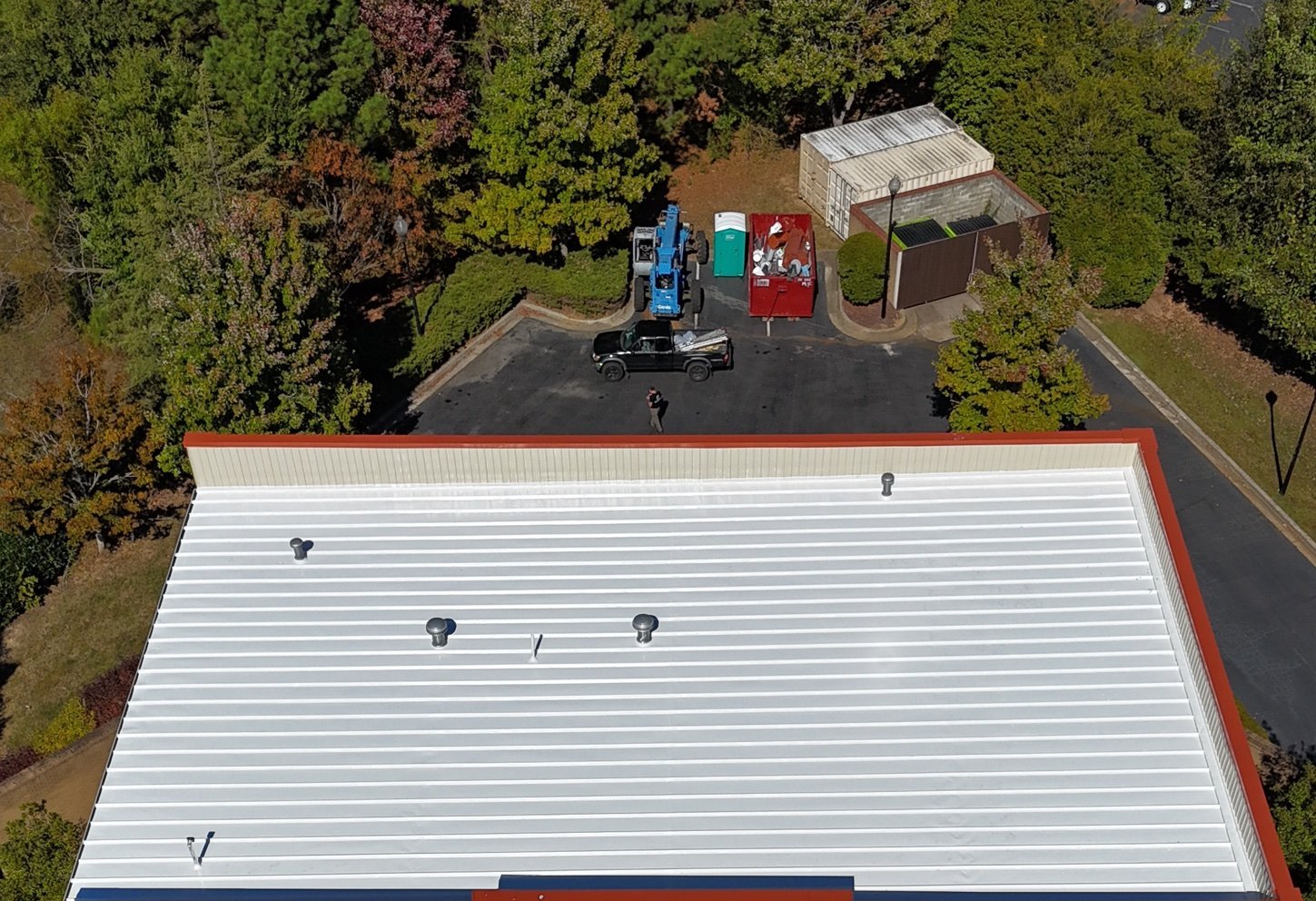 Commercial roofing: metal roof on a two-story office building after a reflective roof coating.