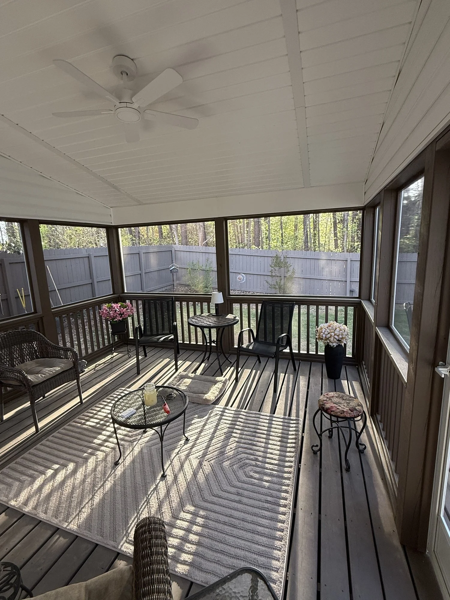 Inside the screened porch: ceiling fan, finished ceiling and full-height screens looking out to the yard.