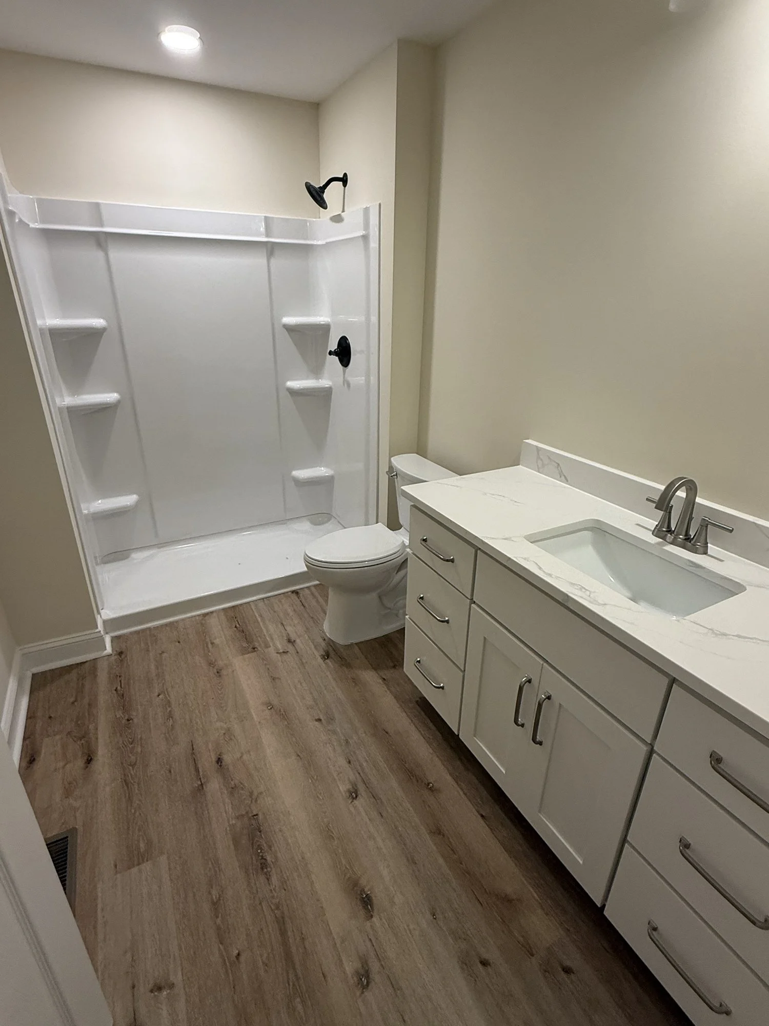 Bathroom remodel: walk-in shower surround, long vanity with new top and fixtures, plank flooring.