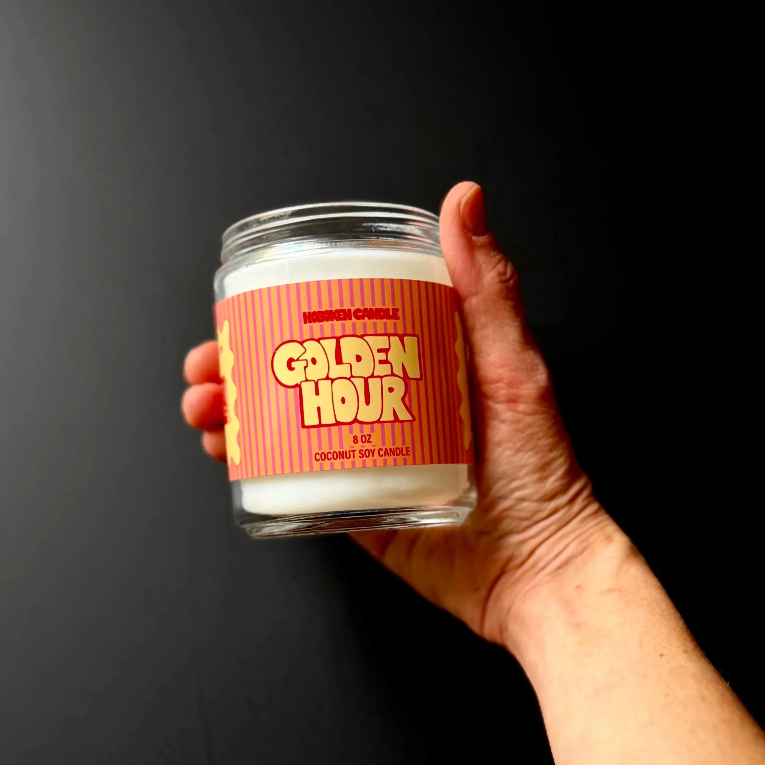 A hand holding a Golden Hour candle from Hoboken Candle