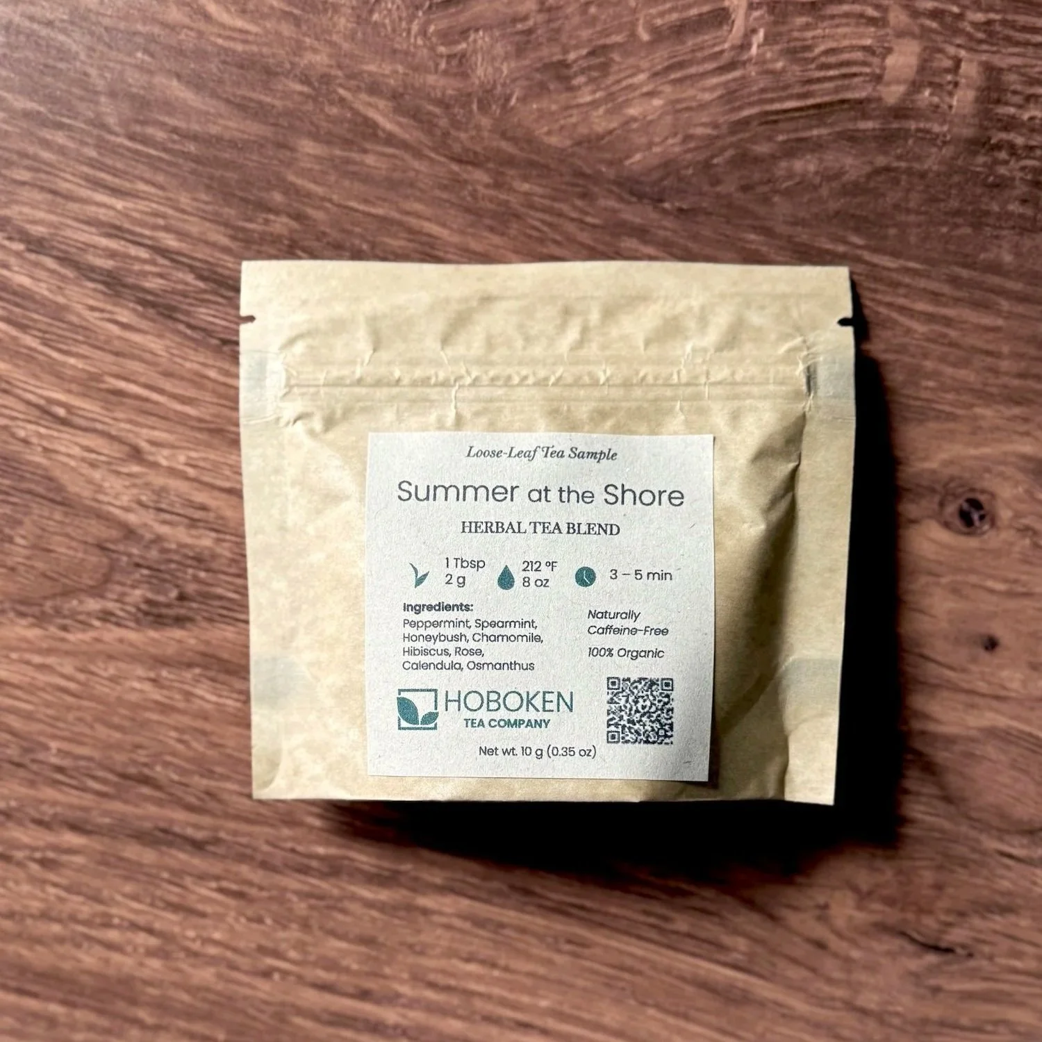 a small brown paper packet of Summer on the Shore caffeine-free herbal loose leaf tea on a wood table