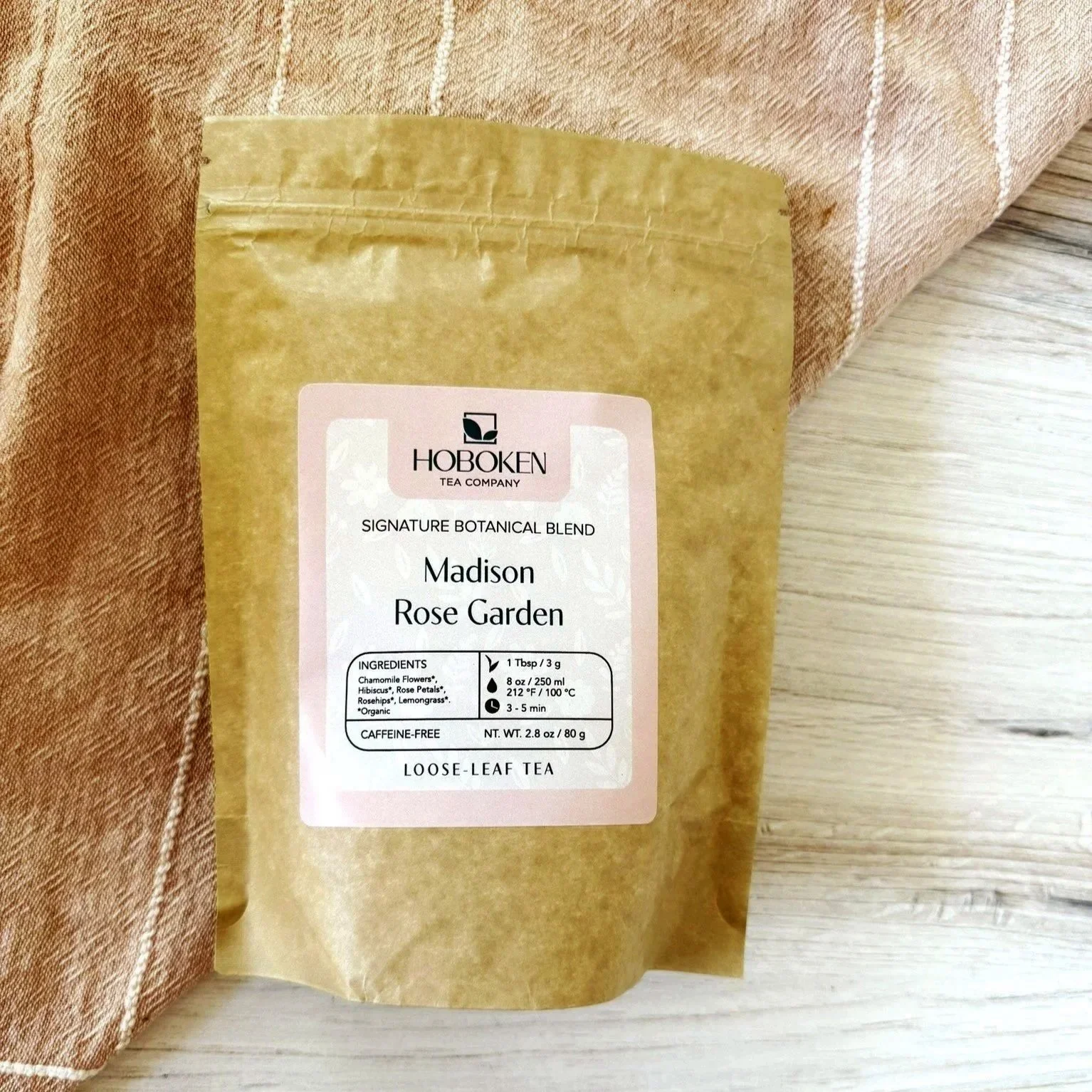 a package of Madison Rose Garden loose leaf organic herbal tea from Hoboken Tea Company on a wood surface with a pink cloth