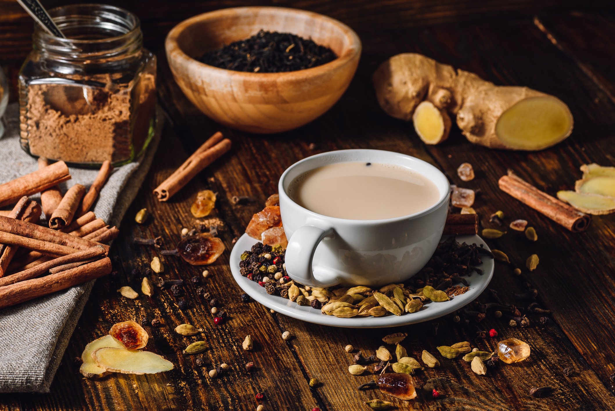 a cup of chai tea on a table surrounded by fresh spices and ginger