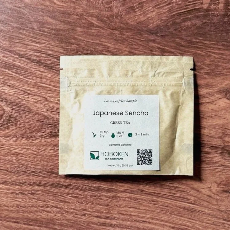 a small paper packet of loose leaf Japanese sencha green tea on a wood table