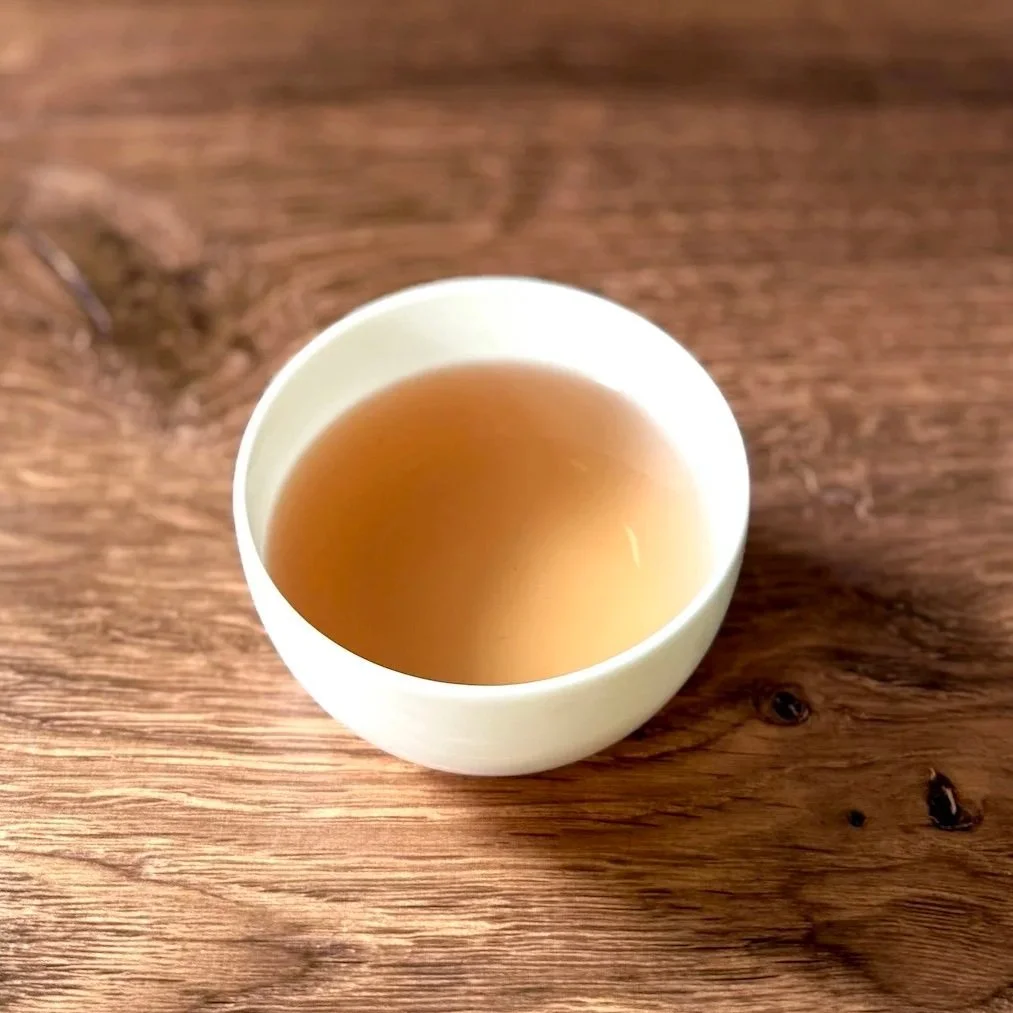 a white bowl of pink herbal tea on a wood table