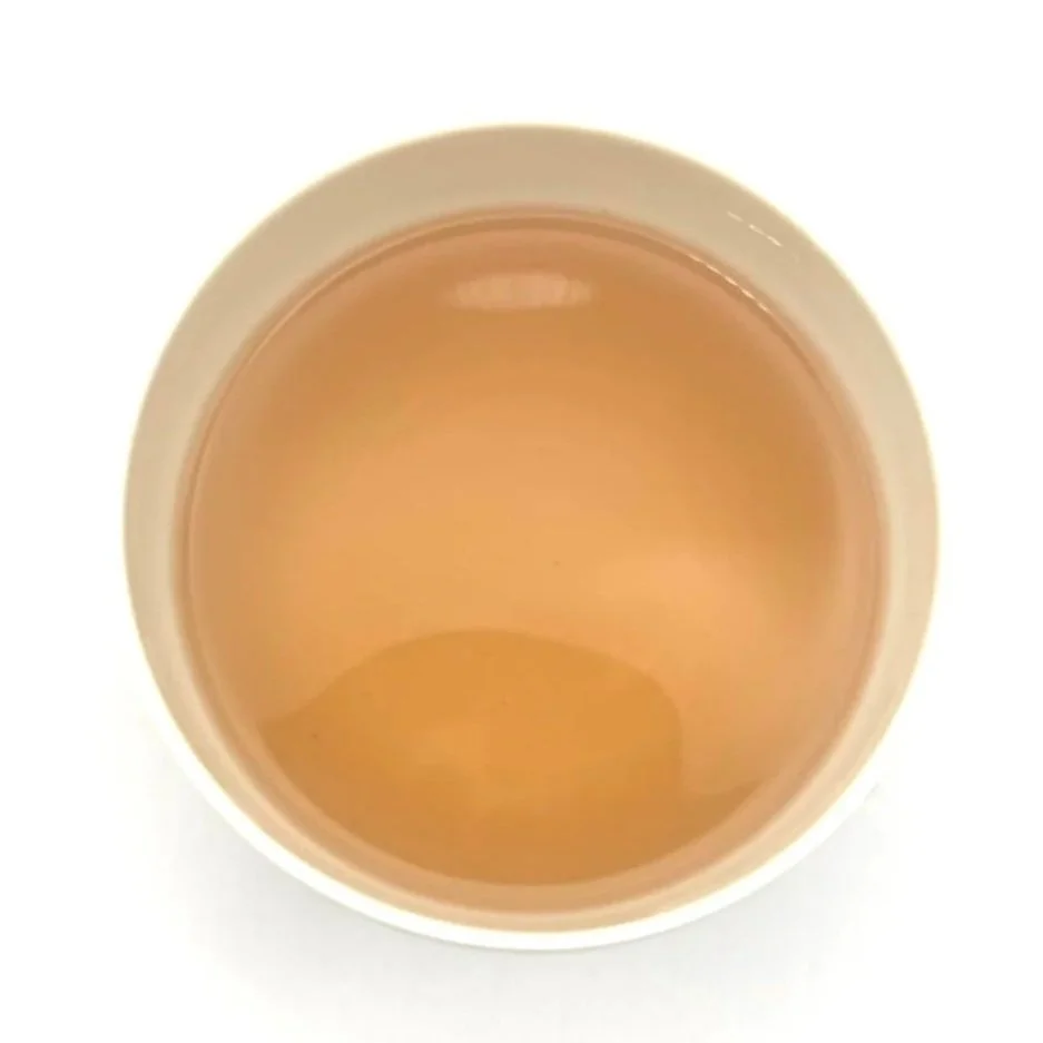 a white bowl of pink herbal tea on a white background