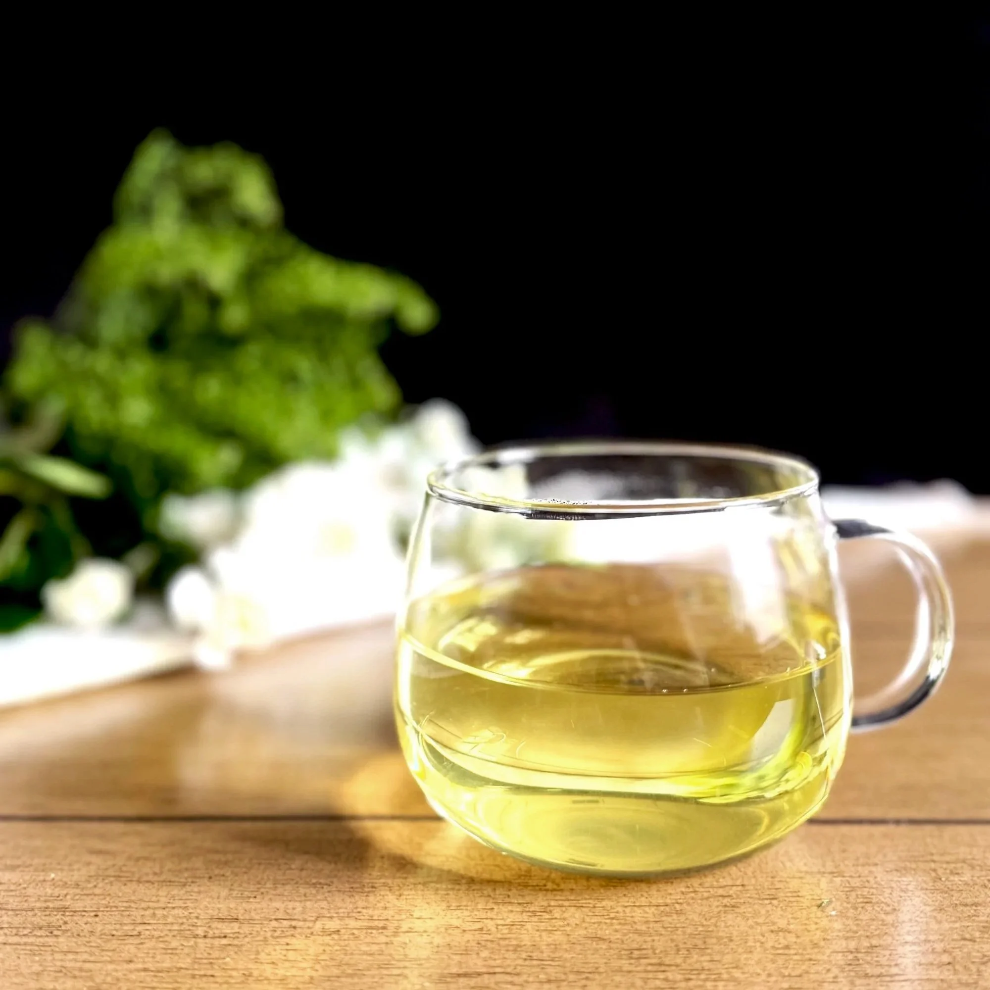 a glass cup of green tea on a wood table with a black background