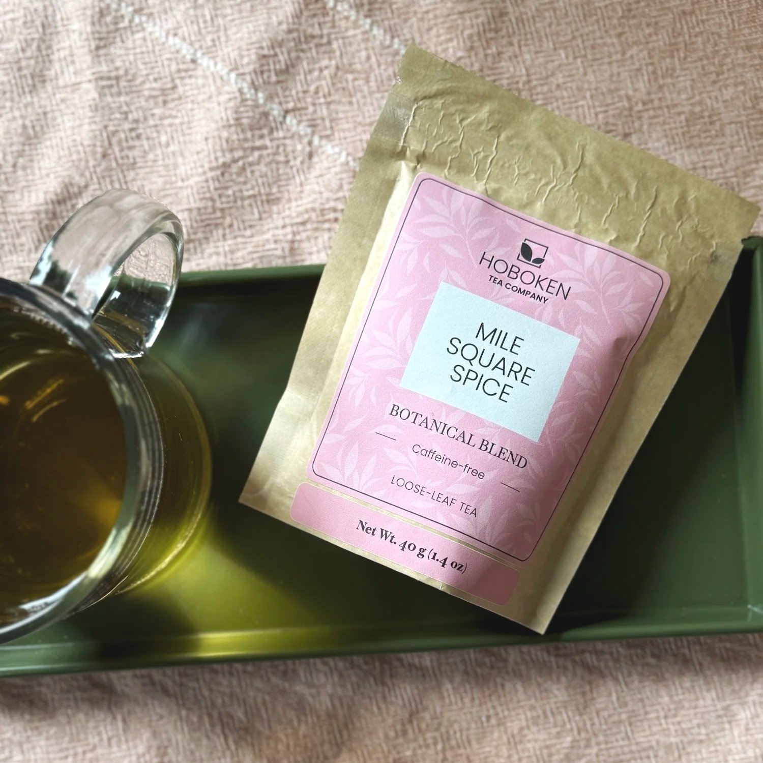 a packet of Mile Square Spice caffeine-free herbal tea on a tray next to a cup of tea