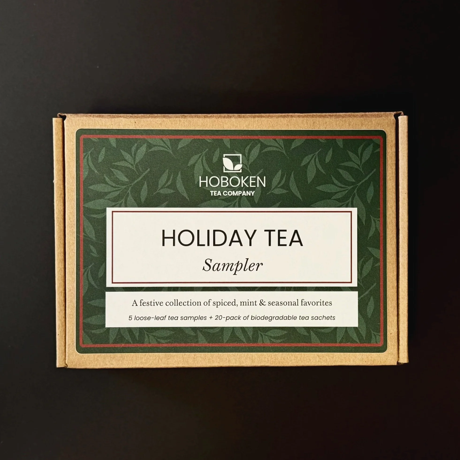 A box labeled Holiday Tea Sampler from Hoboken Tea Company on a black surface