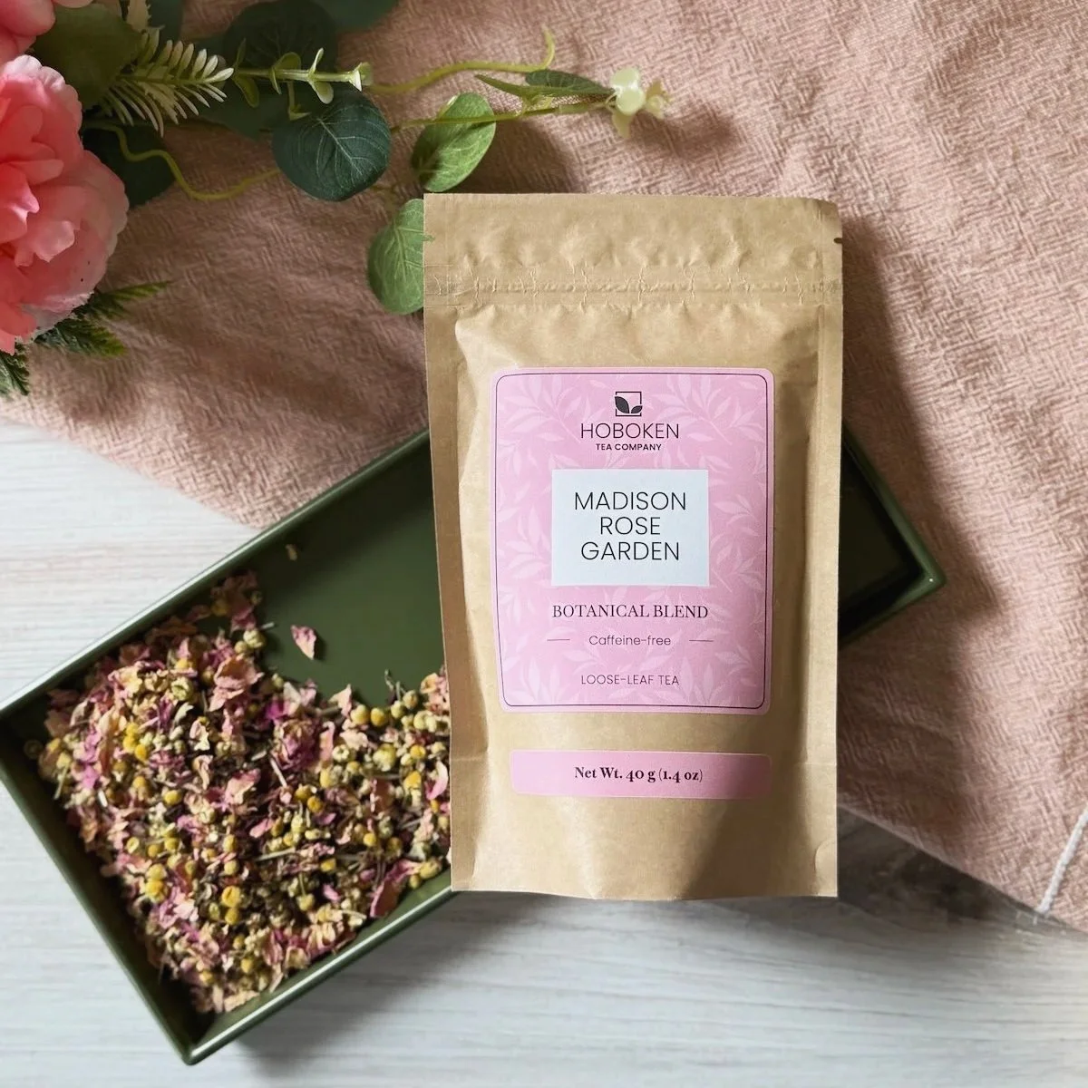 a package of Madison Rose Garden herbal tea on a tray with a pile of loose leaf hibiscus rose tea