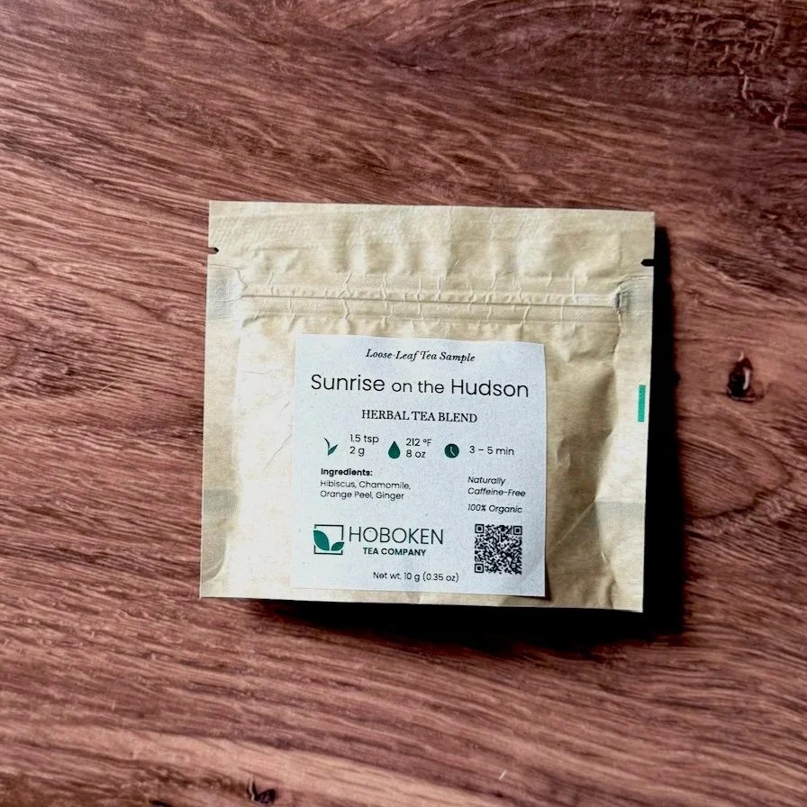 a small brown paper packet of Sunrise on the Hudson herbal tea on a wood table
