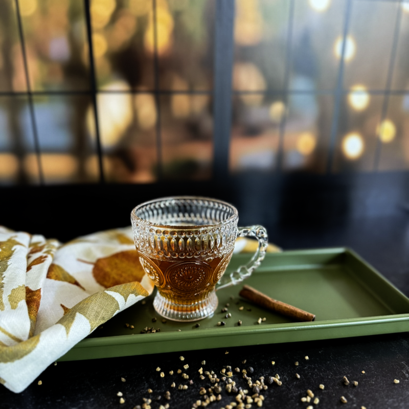 a cup of black tea on a table in front of a window at night