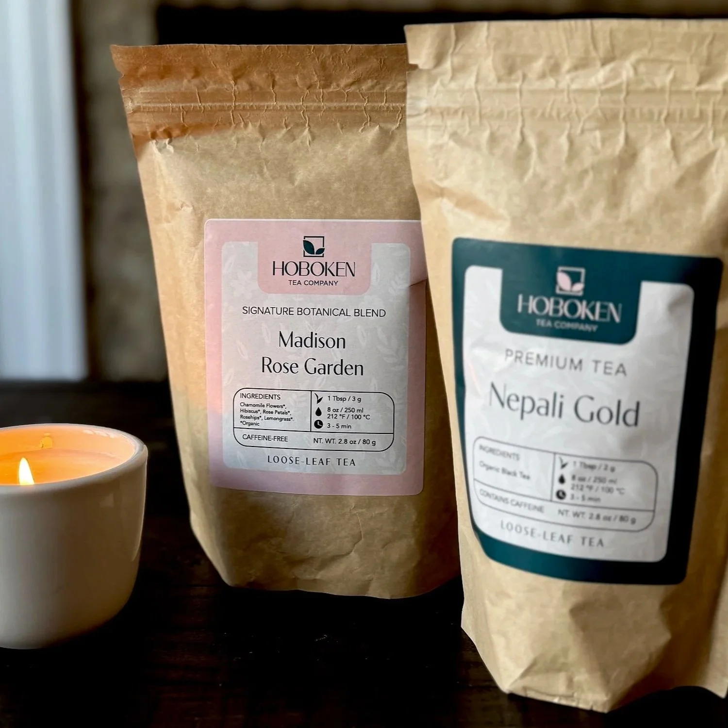 two packets of Hoboken Tea Company loose leaf tea on a table with a lighted candle