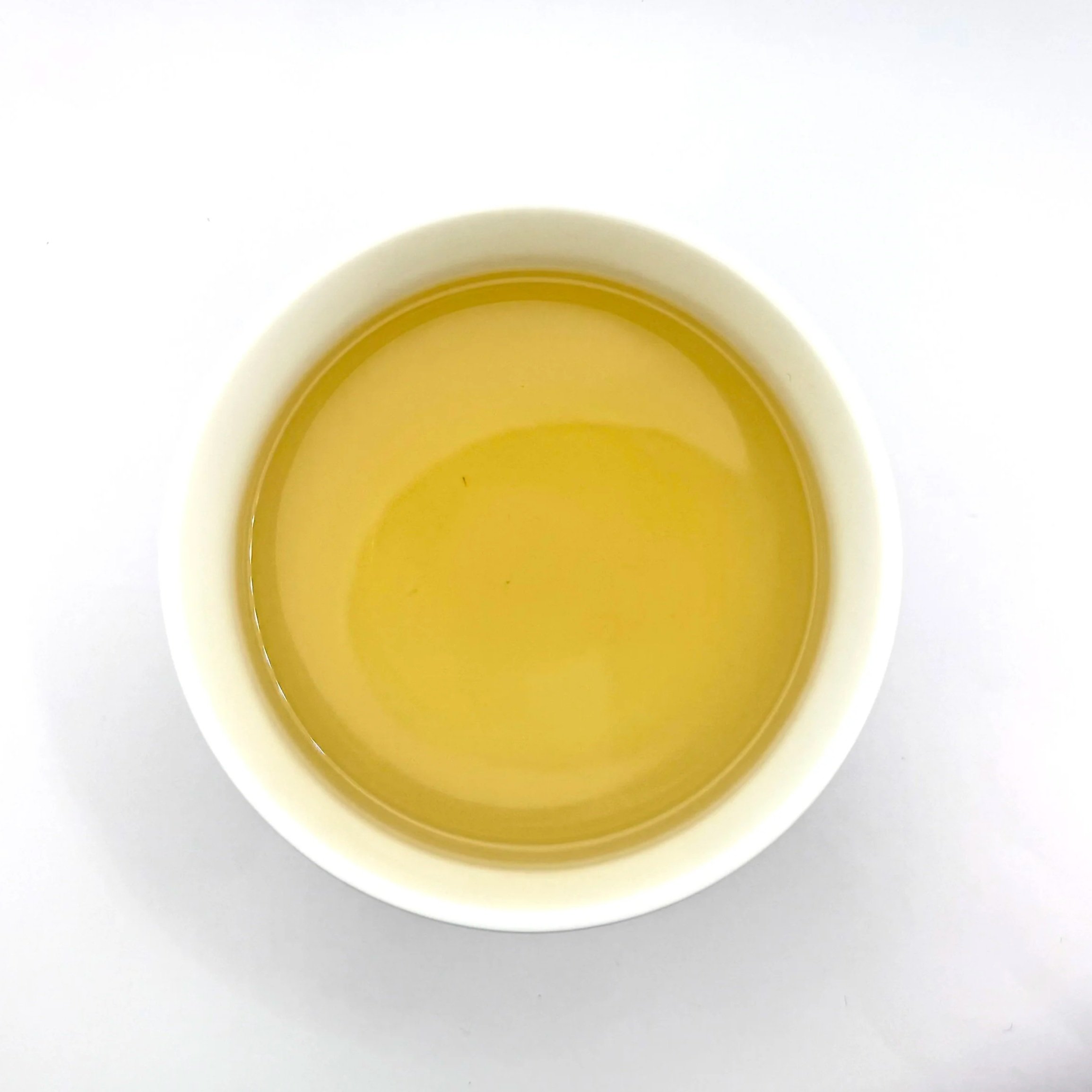 an overhead view of a cup of pale yellow Snow Day herbal tea in a white bowl