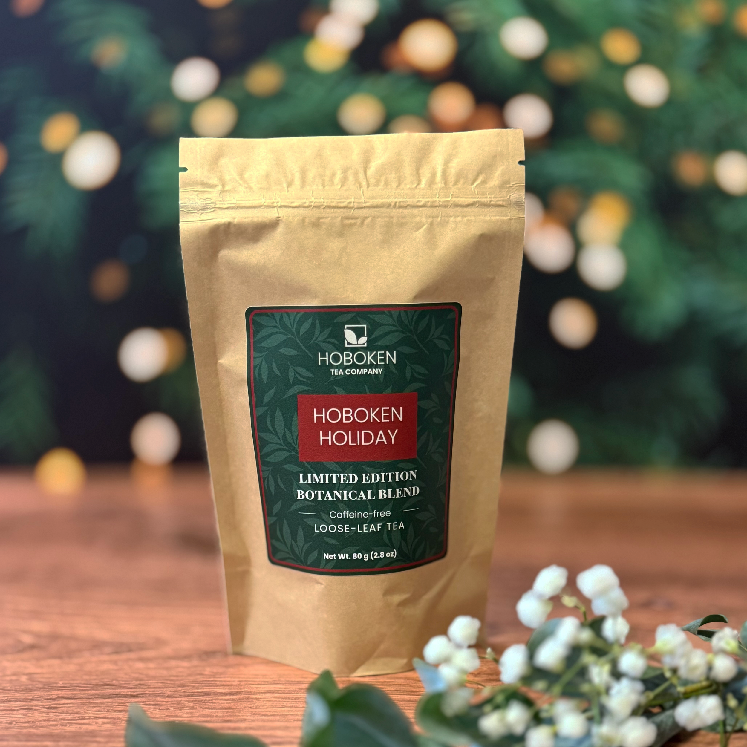 a package of Hoboken Holiday caffeine-free herbal loose leaf tea from Hoboken Tea Company in front of a Christmas tree with lights