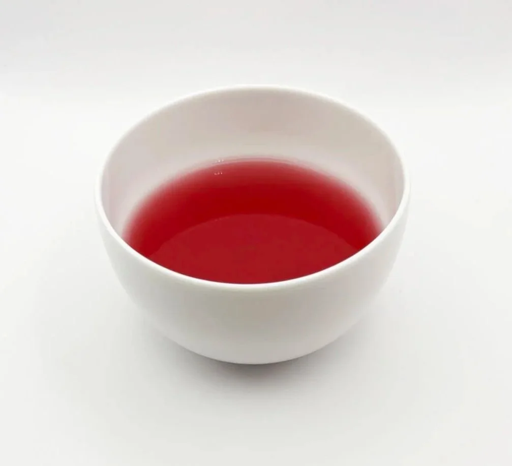 a white bowl of red hibiscus organic herbal tea on a white background