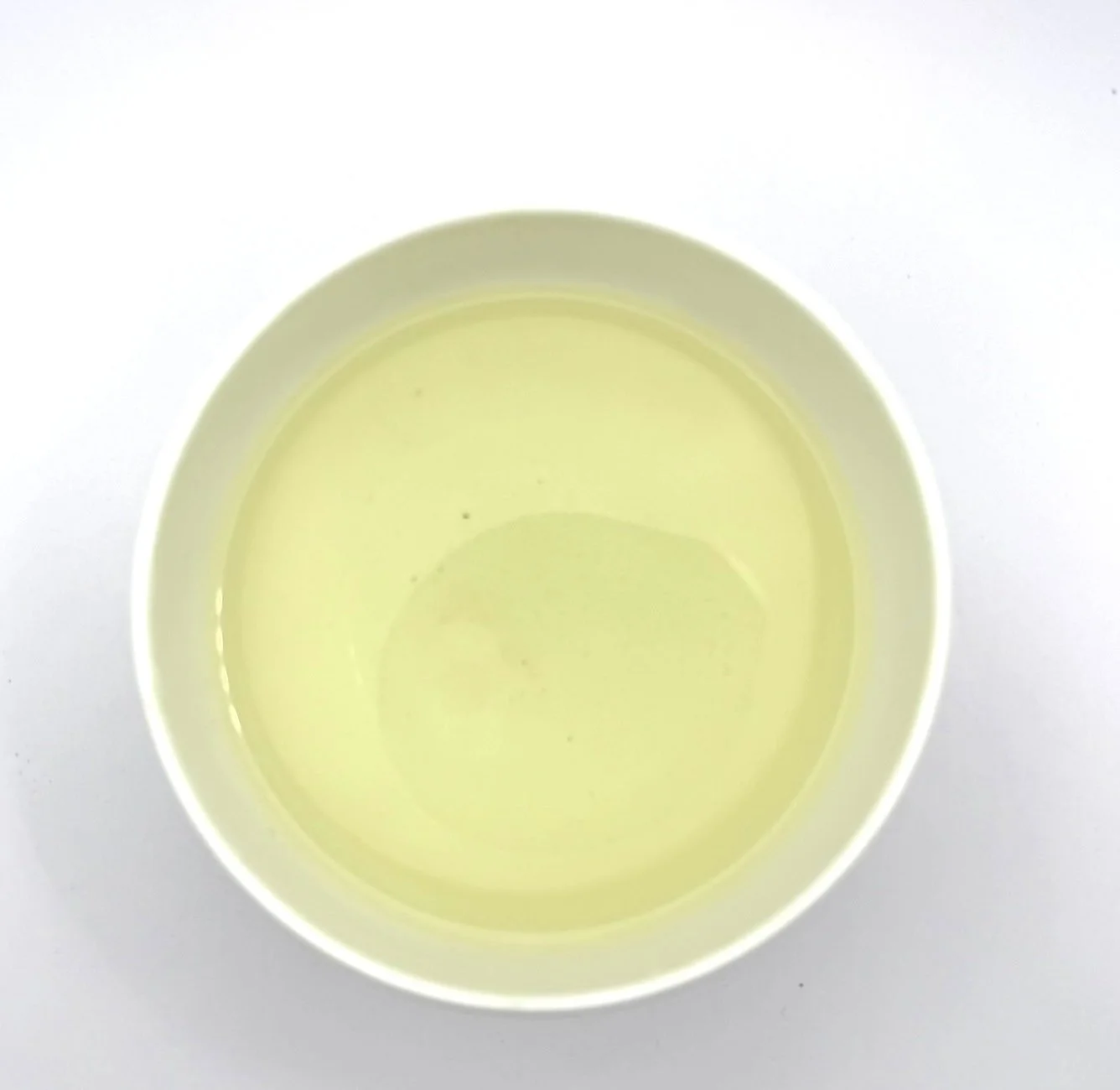 a white bowl of organic green tea on a white background