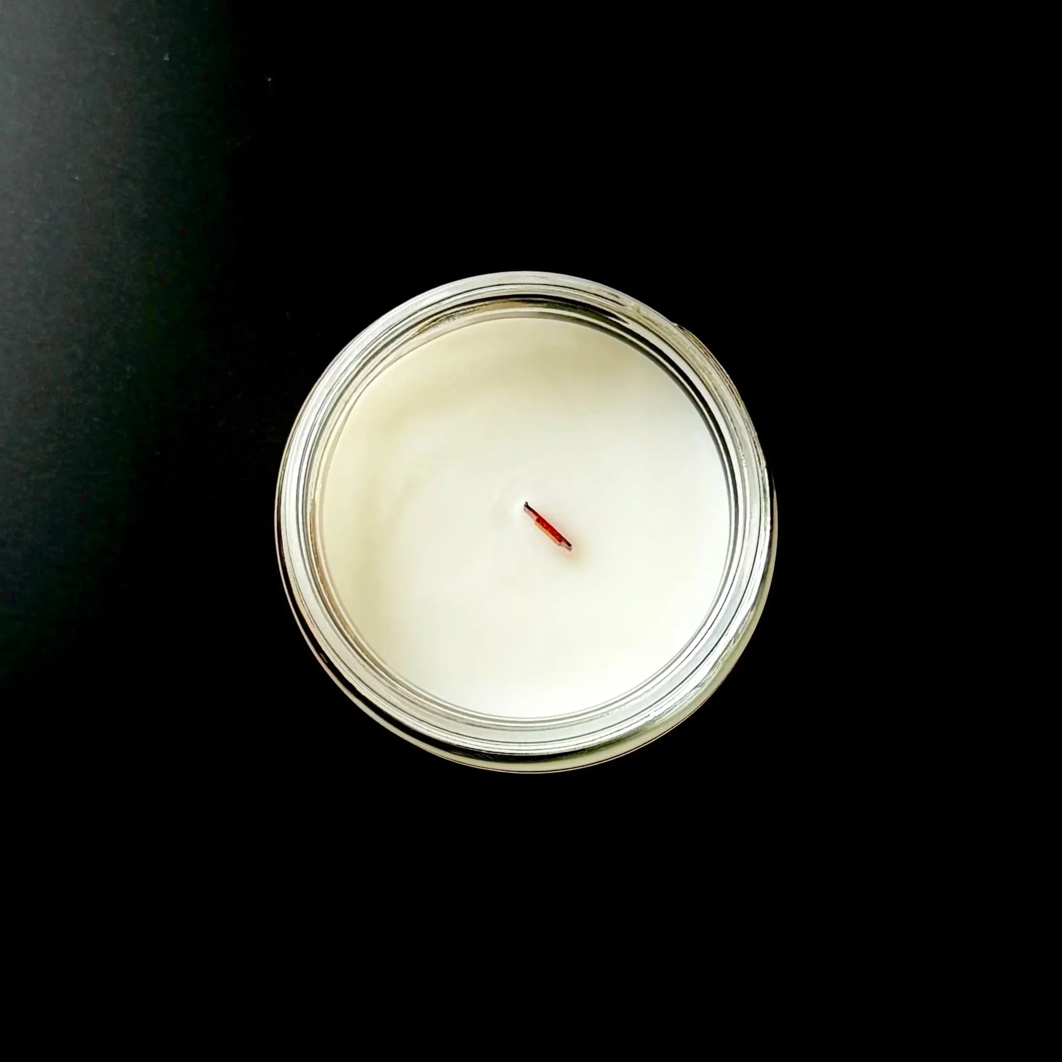 overhead view of a white candle with a bamboo wick in a glass container