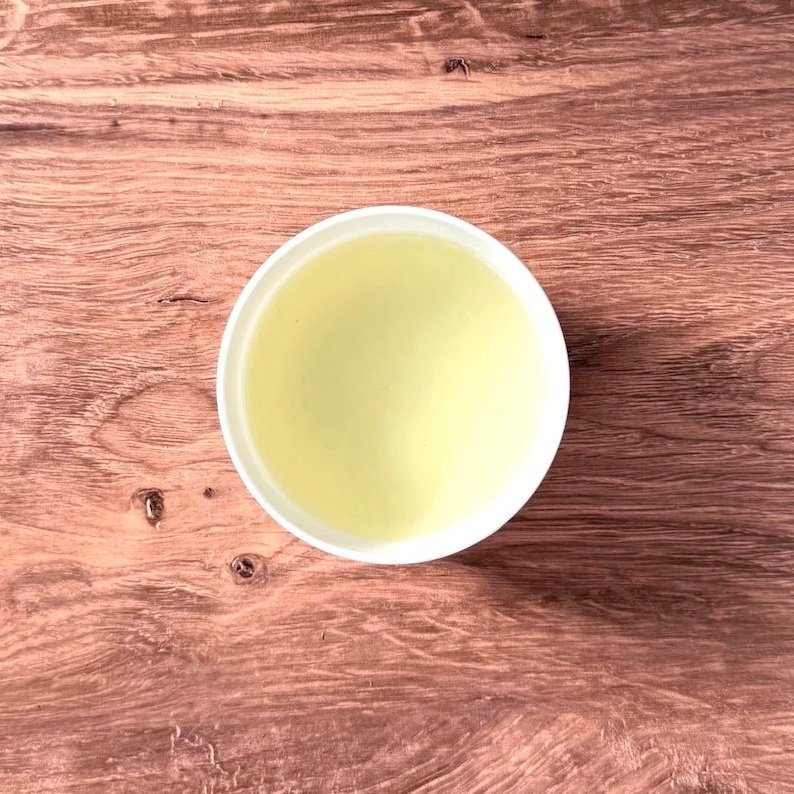 a white bowl of green tea on a wood background