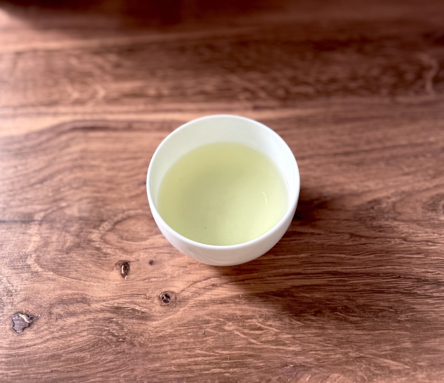 a white bowl of organic green tea on a wood table