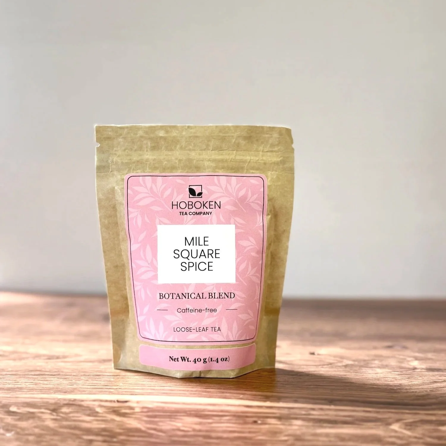 a small brown paper pouch of Sunrise on the Hudson herbal tea with a pink label on a white background
