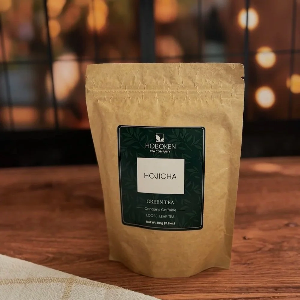 A package of loose leaf Hojicha green tea from Hoboken Tea Company on a wood table in front of a window