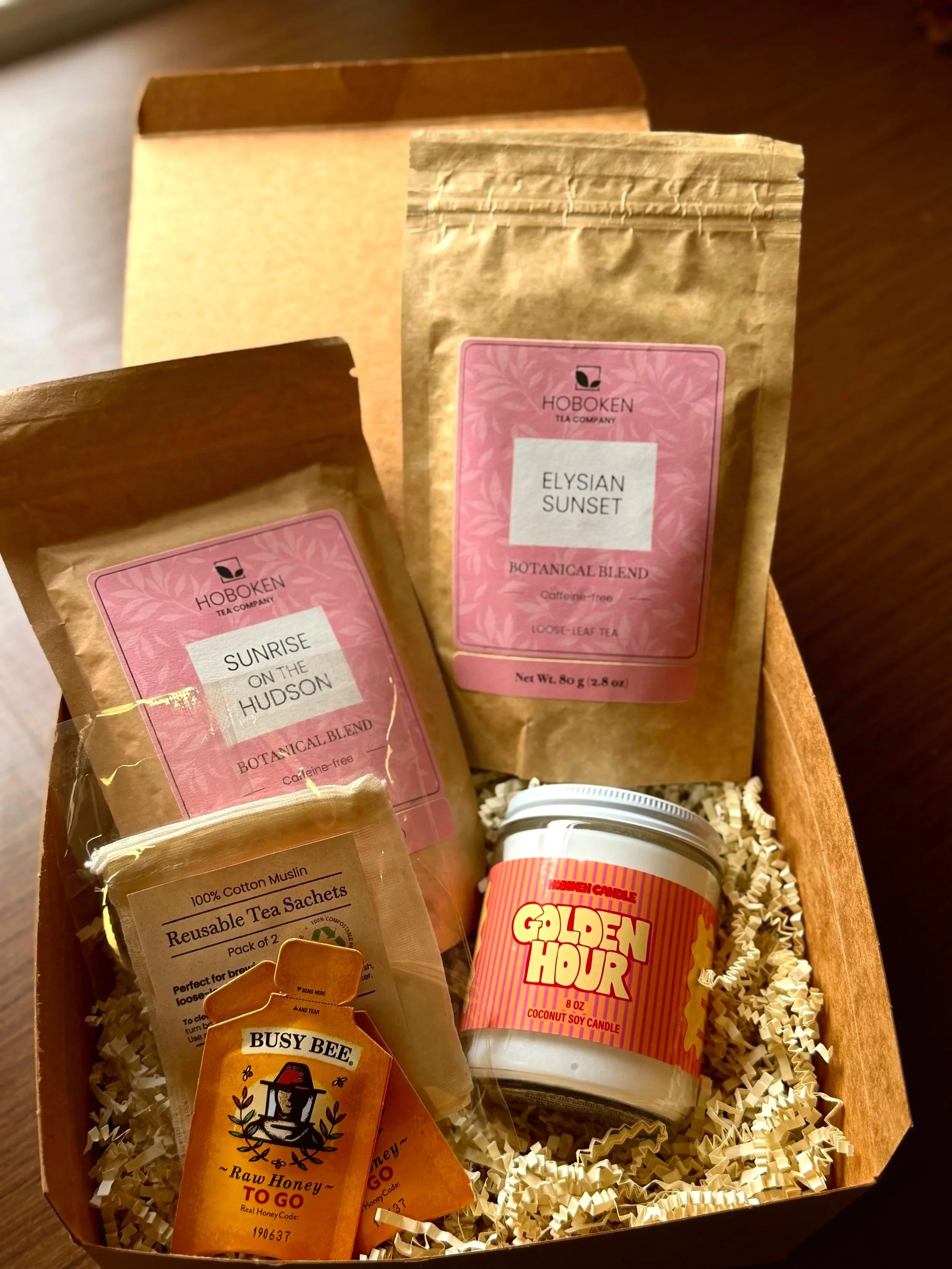 An open box containing packets of loose leaf tea, a candle, and other items