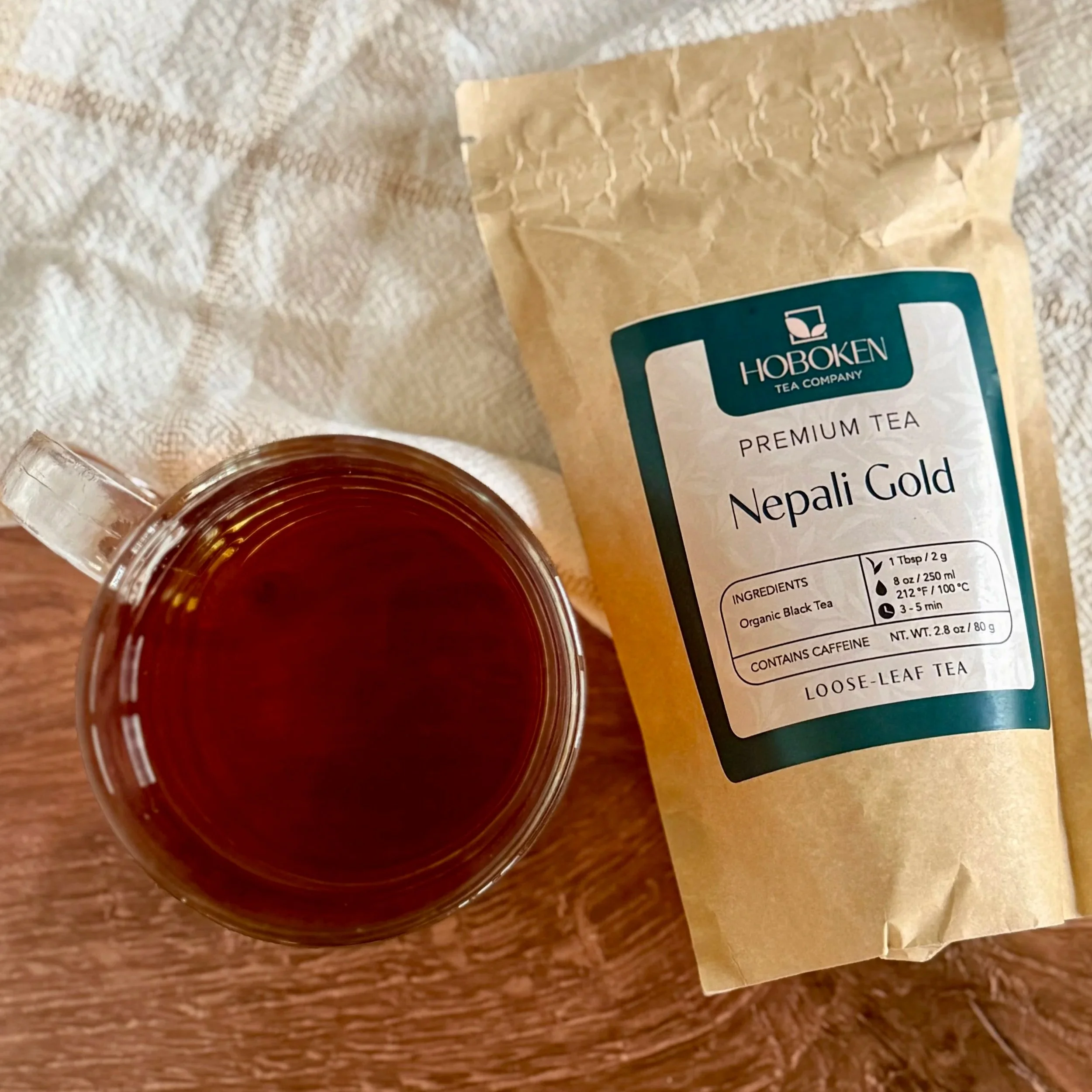 A mug of organic black tea next to a package of Hoboken Tea Company loose leaf tea