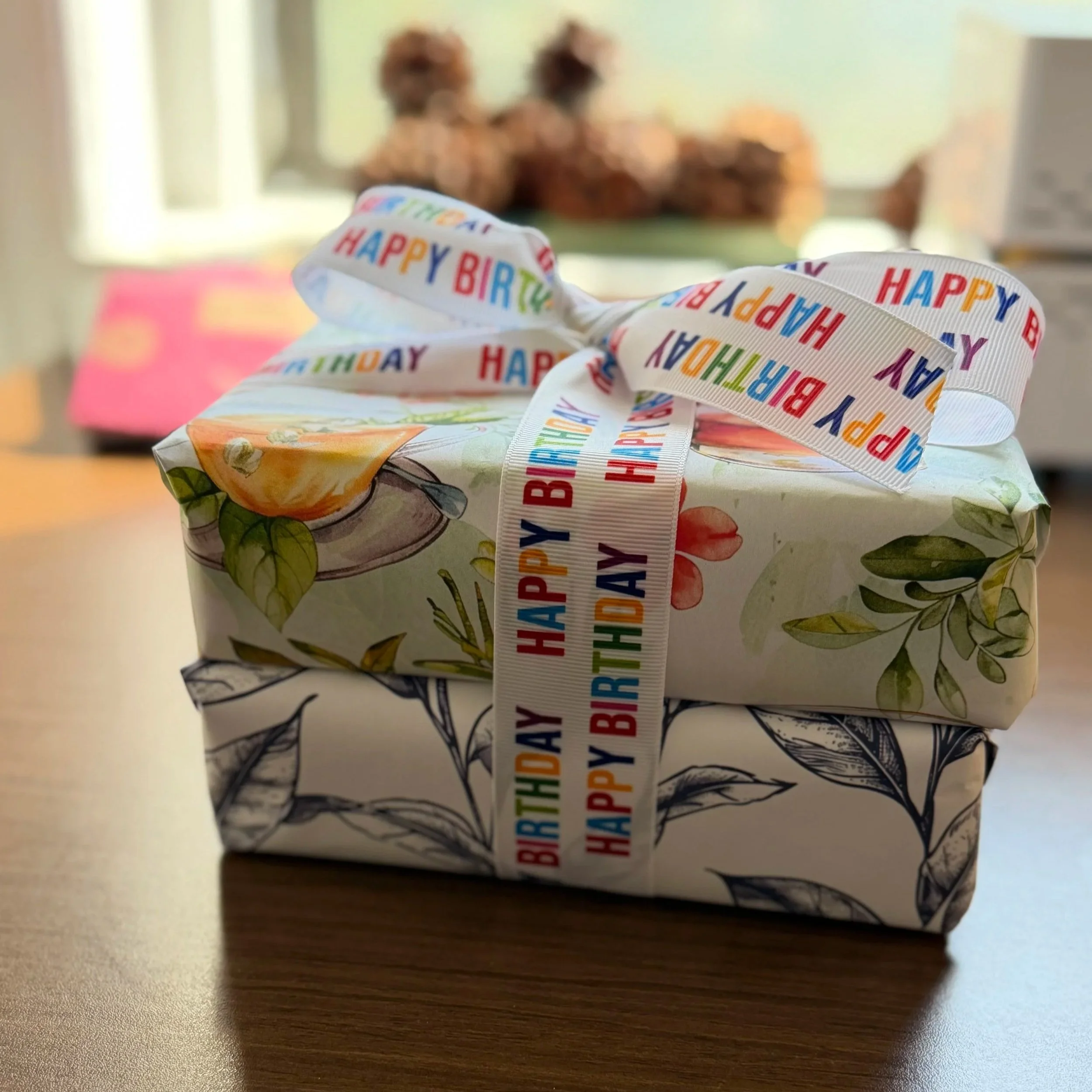 two small boxes wrapped in colorful wrapping paper tied together with a Happy Birthday ribbon