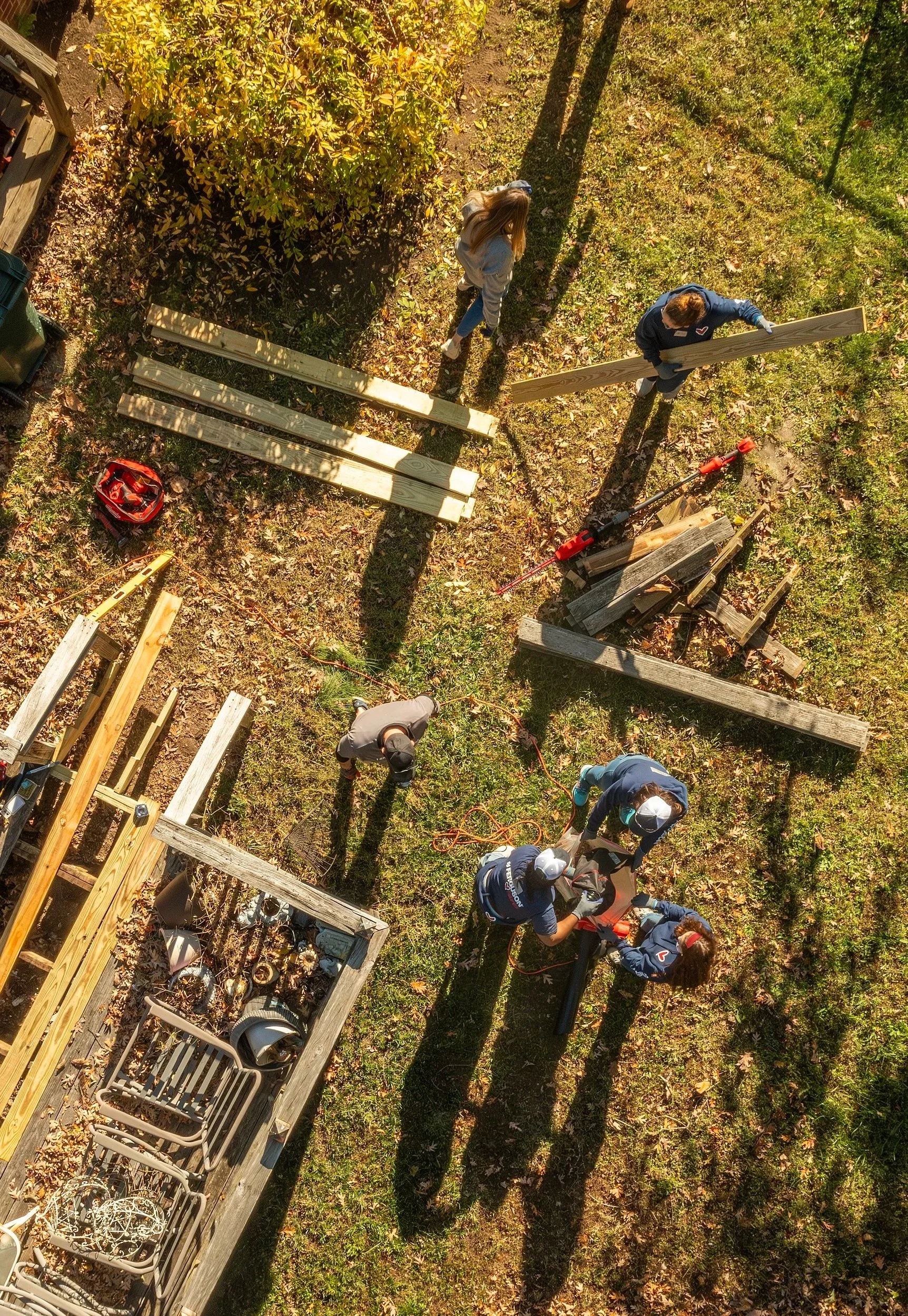 People working together outdoors installing wooden planks for a project.