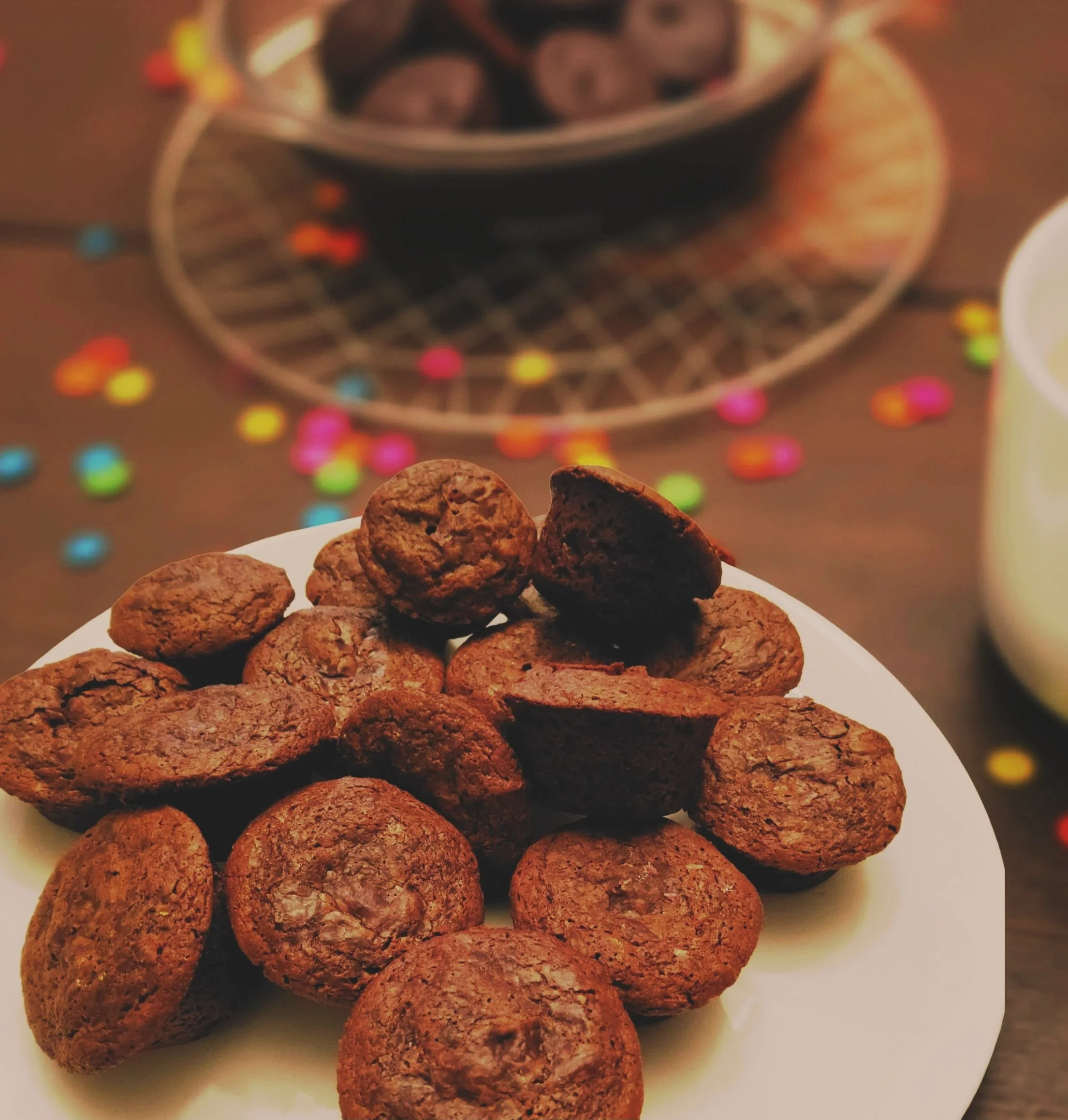 Plate of vegan chocolate brownie bites on a table with colorful confetti and a bowl of more brownie bites in the background.