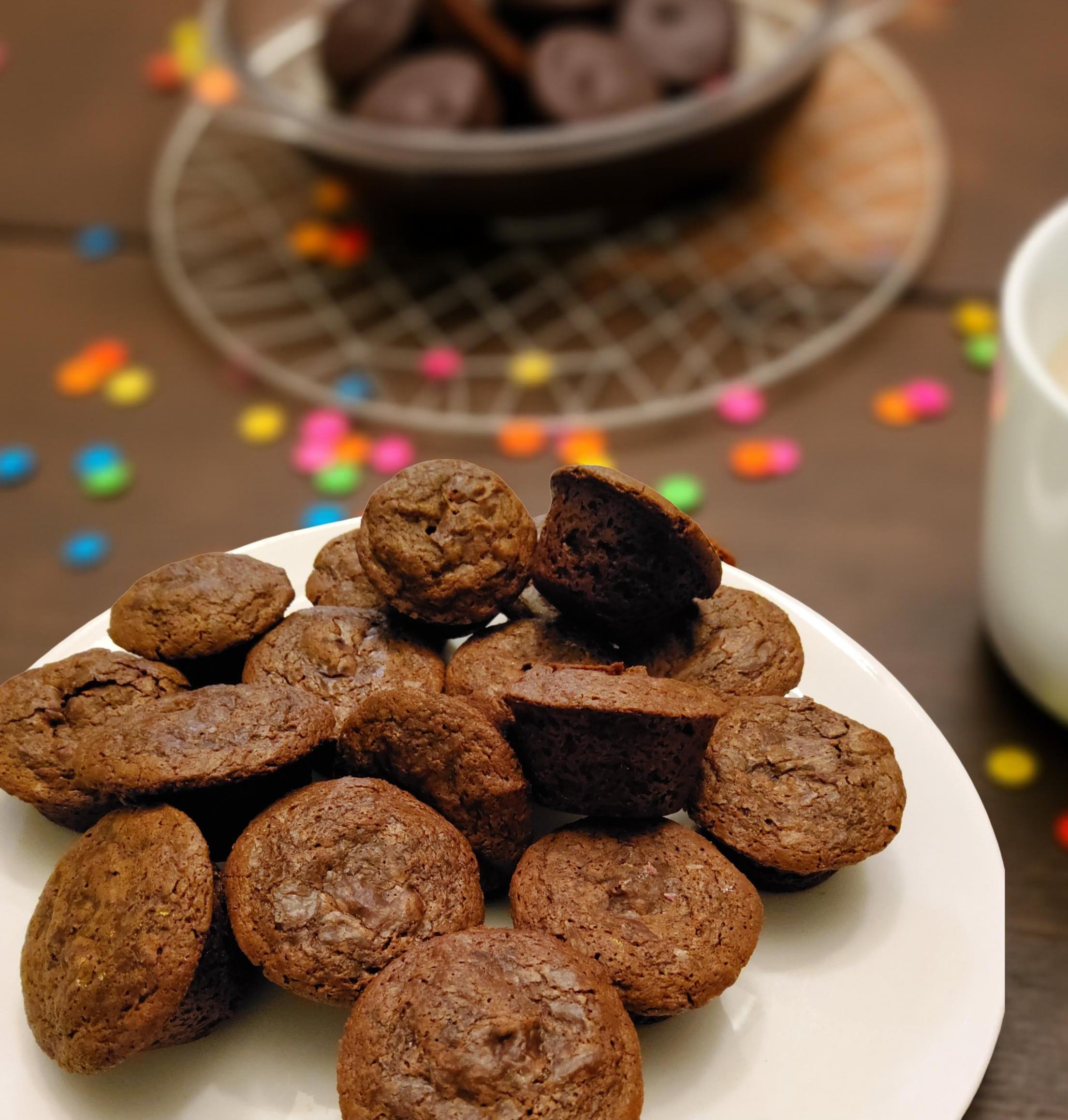 Plate of vegan chocolate brownie bites on a table with colorful confetti and a bowl of more brownie bites in the background.