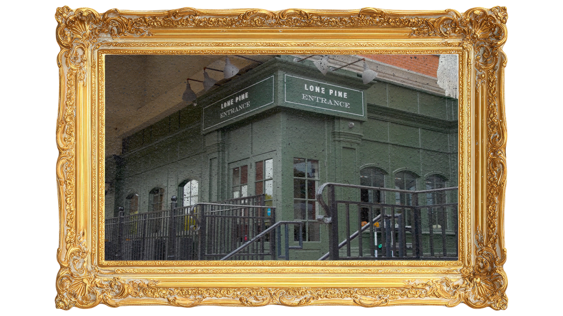 A green building with a sign that reads 'Lone Pine Entrance' and a staircase leading up to the entrance.