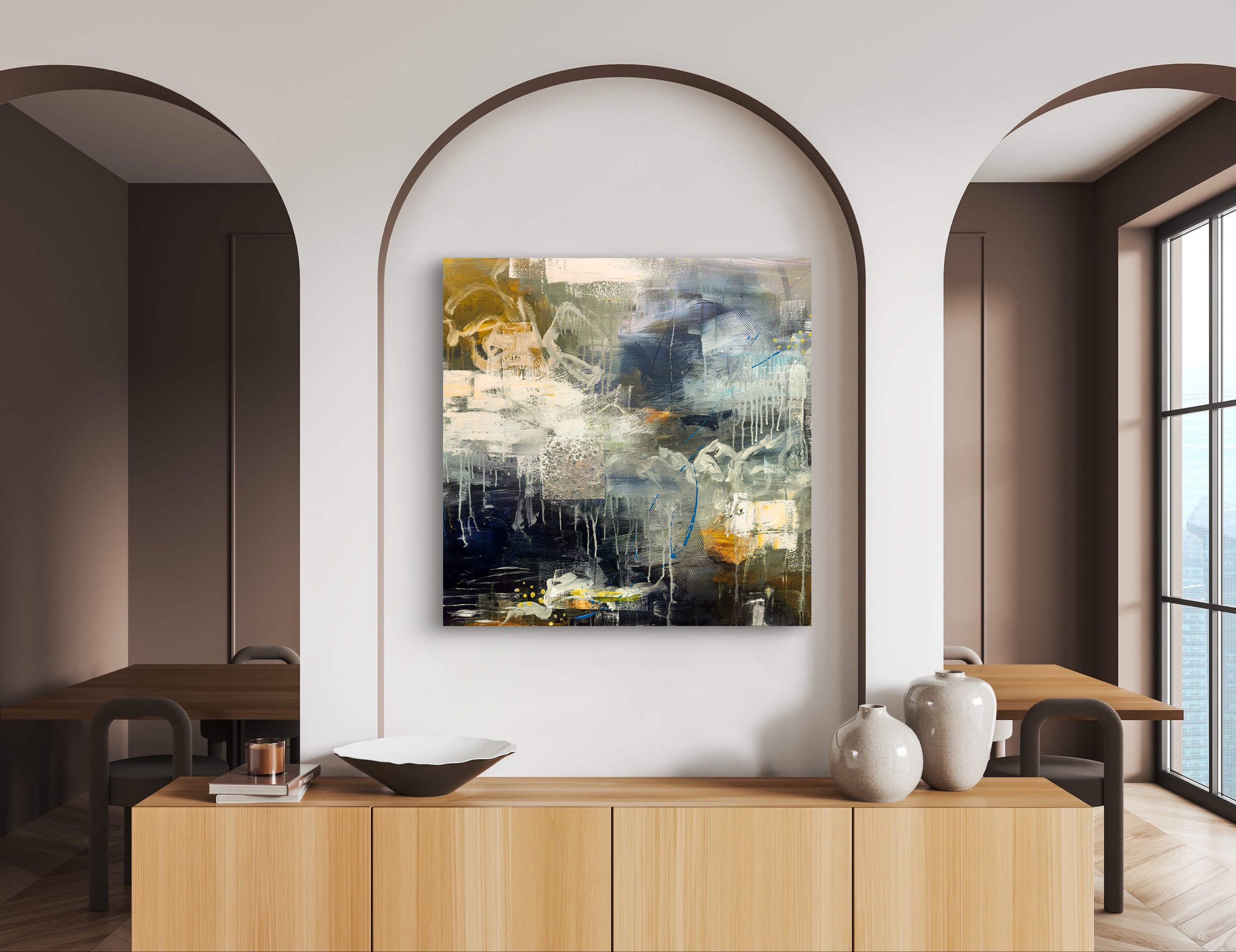 Modern living room with abstract painting on white wall, wooden table with vases and decor, and large windows with city view.