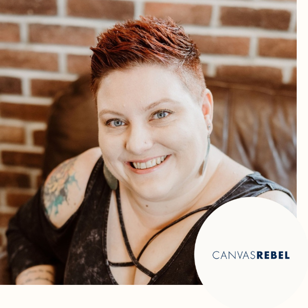 Smiling woman with short reddish hair, tattoos on her arm, wearing a black top, sitting on a brown leather couch against a brick wall, with a CANVASREBEL logo in the corner.