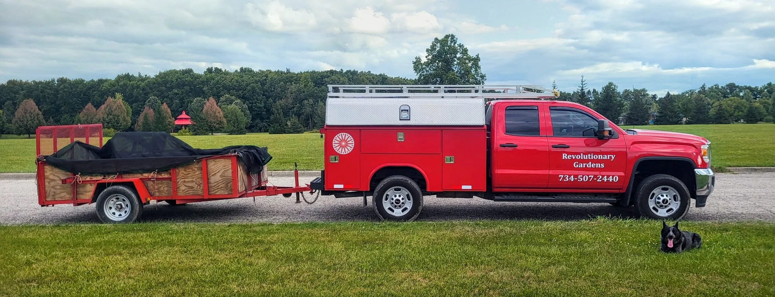Red Revolutionary Gardens Truck with a landscaping trailer