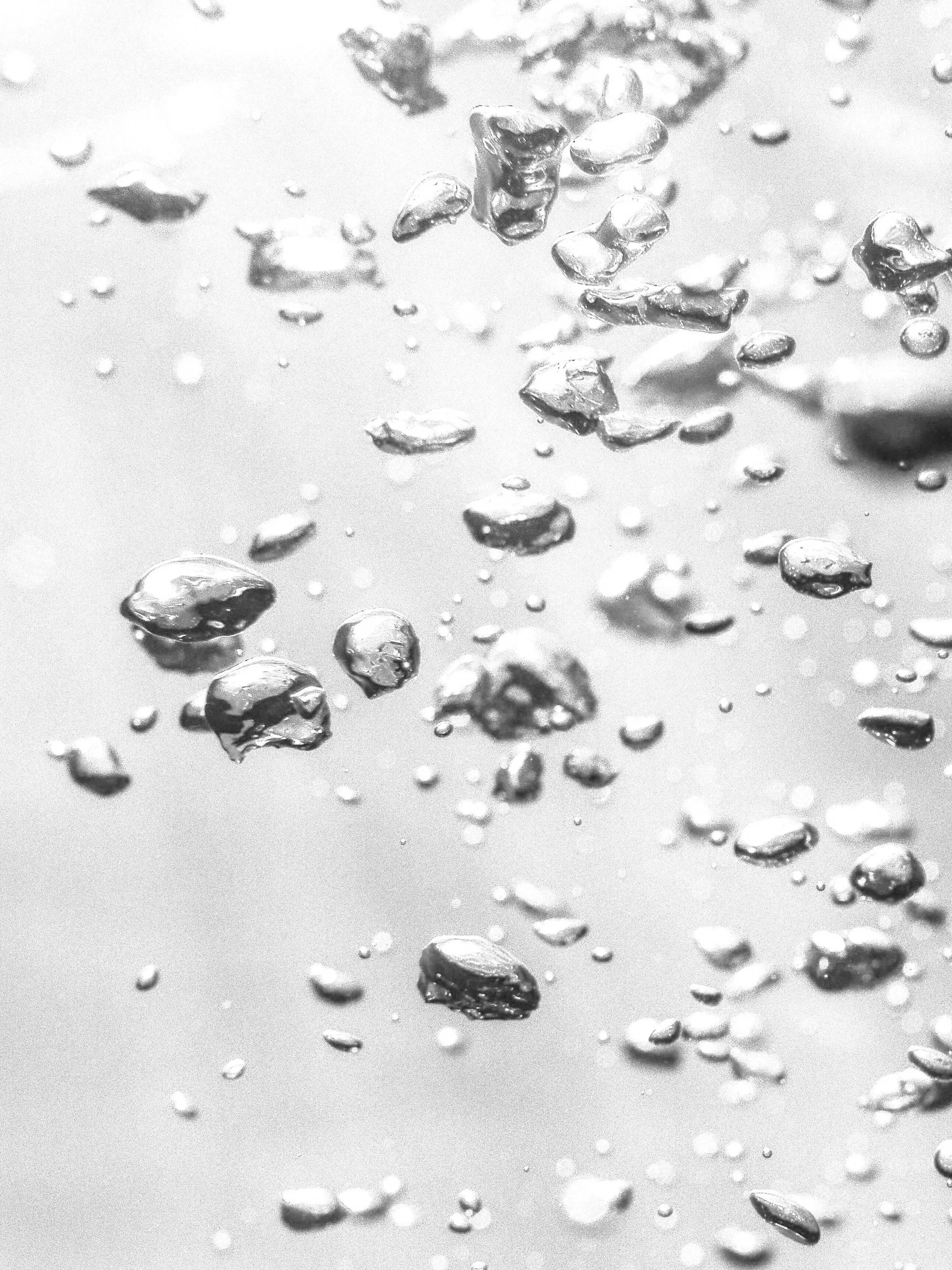 Close-up of water droplets on a reflective surface, with some droplets larger and more prominent.