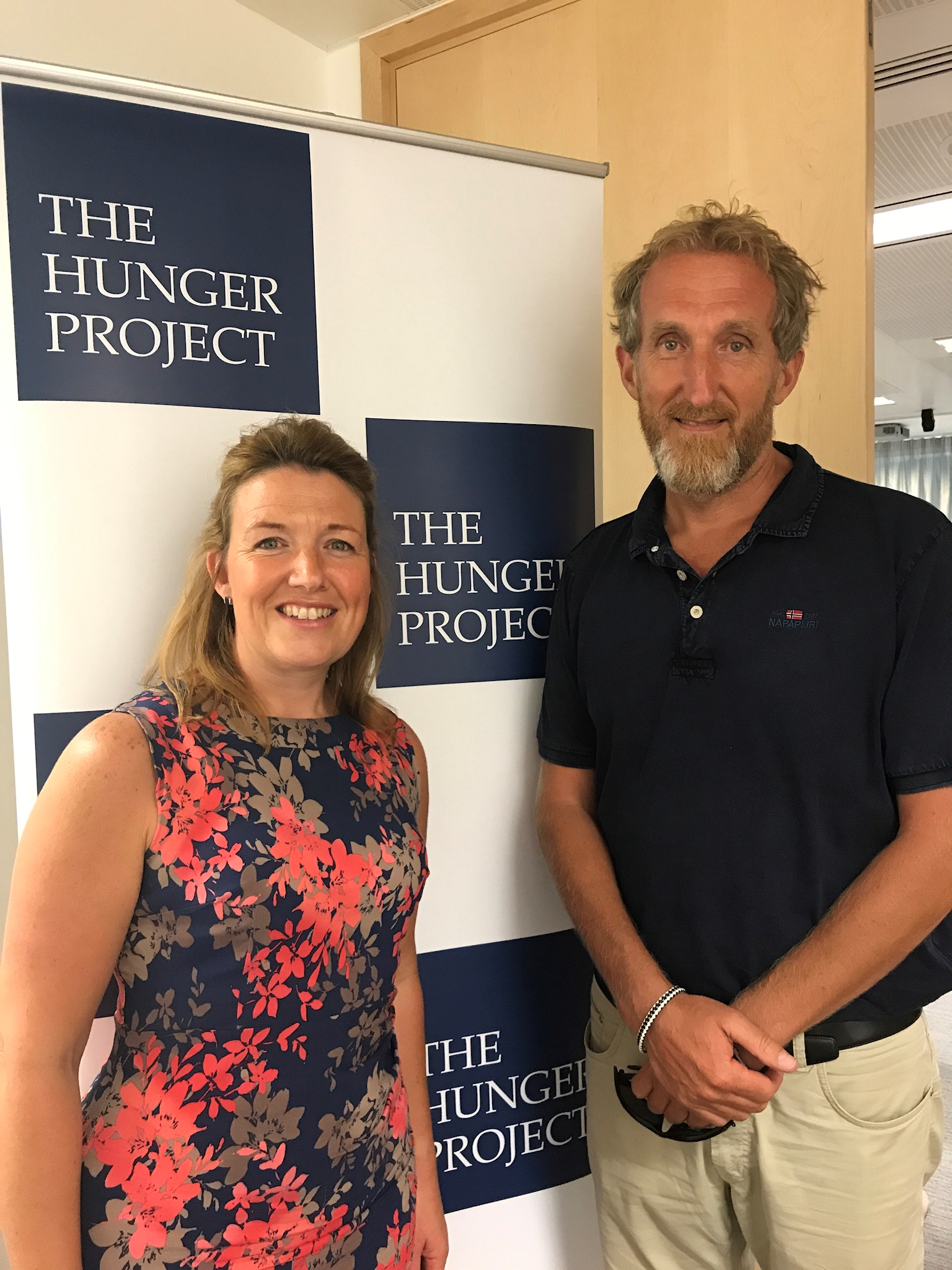 Teresa standing next to The Hunger Project Banner