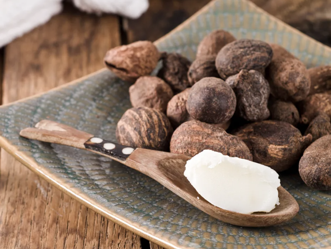 A close-up of a plate with ball-shaped truffles and a spoon with white substance, possibly butter, on a rustic wooden surface.