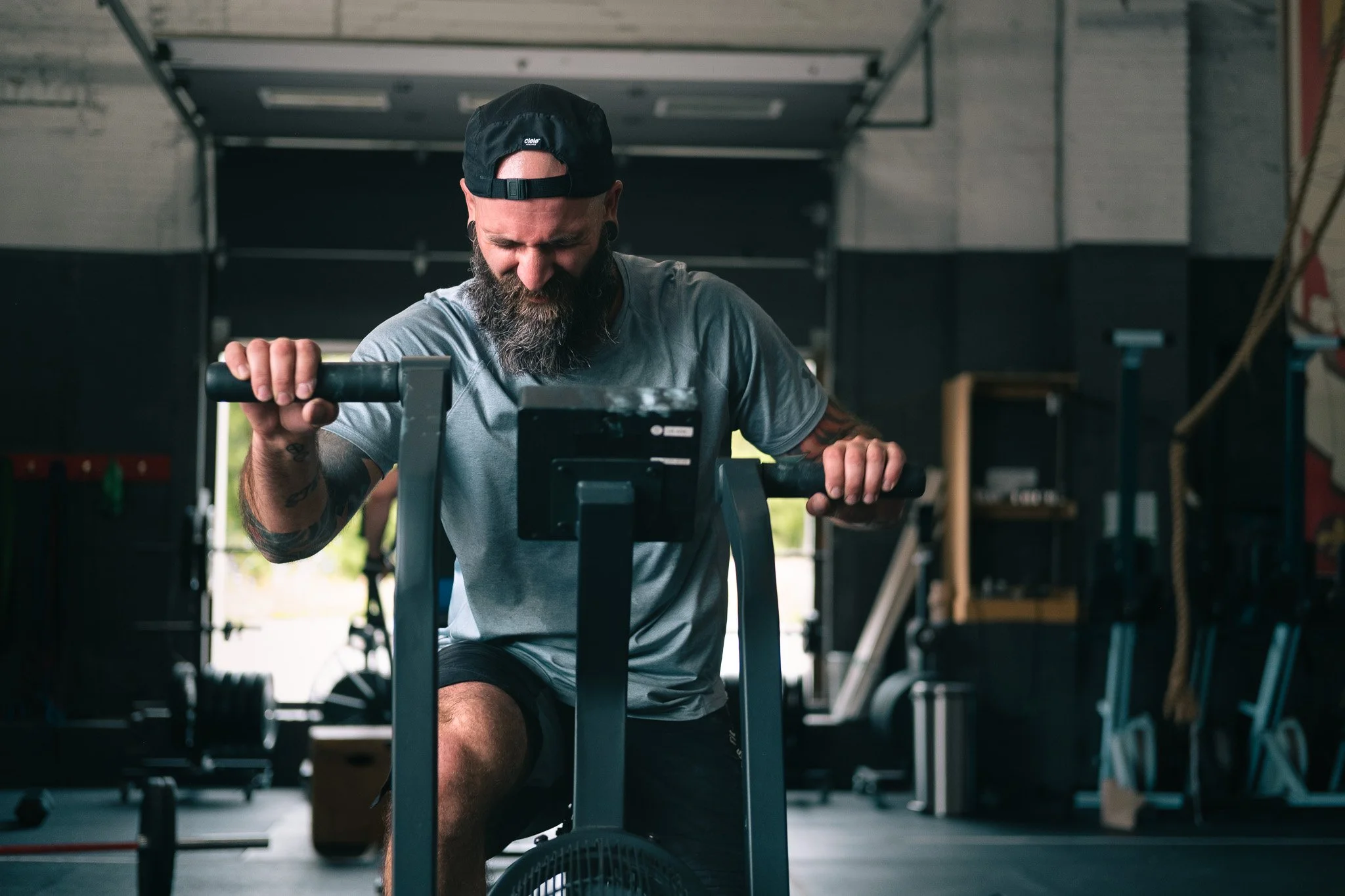 Homme barbu en train de faire du vélo d'appartement dans une salle de sport.