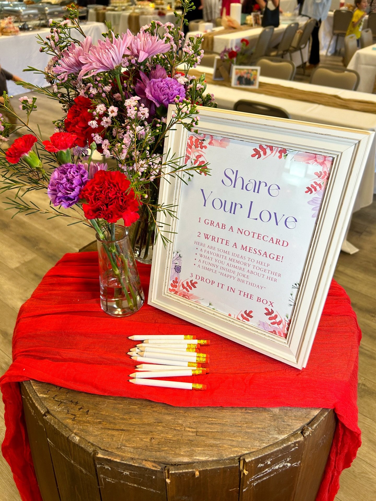 March 8, 2025: Once inside they had the opportunity to write a special note for the guest of honor. We set up this activity on our Rustic Barrels, and finished them off with a red cheesecloth runner and some beautiful floral arrangements one Signatur