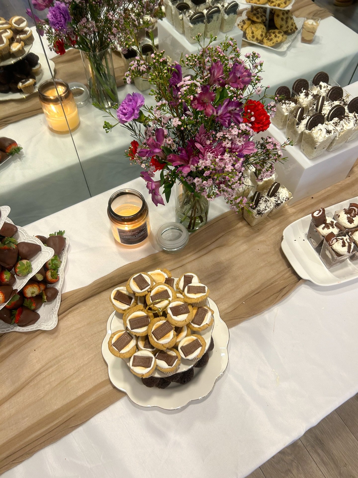 March 8, 2025: To create a beautiful atmosphere we utilized our white and canvas tablecloths with a brown cheesecloth runner. To top it off we added a variety of petite and dainty vases in reds and purples for the centerpieces. The color scheme was p