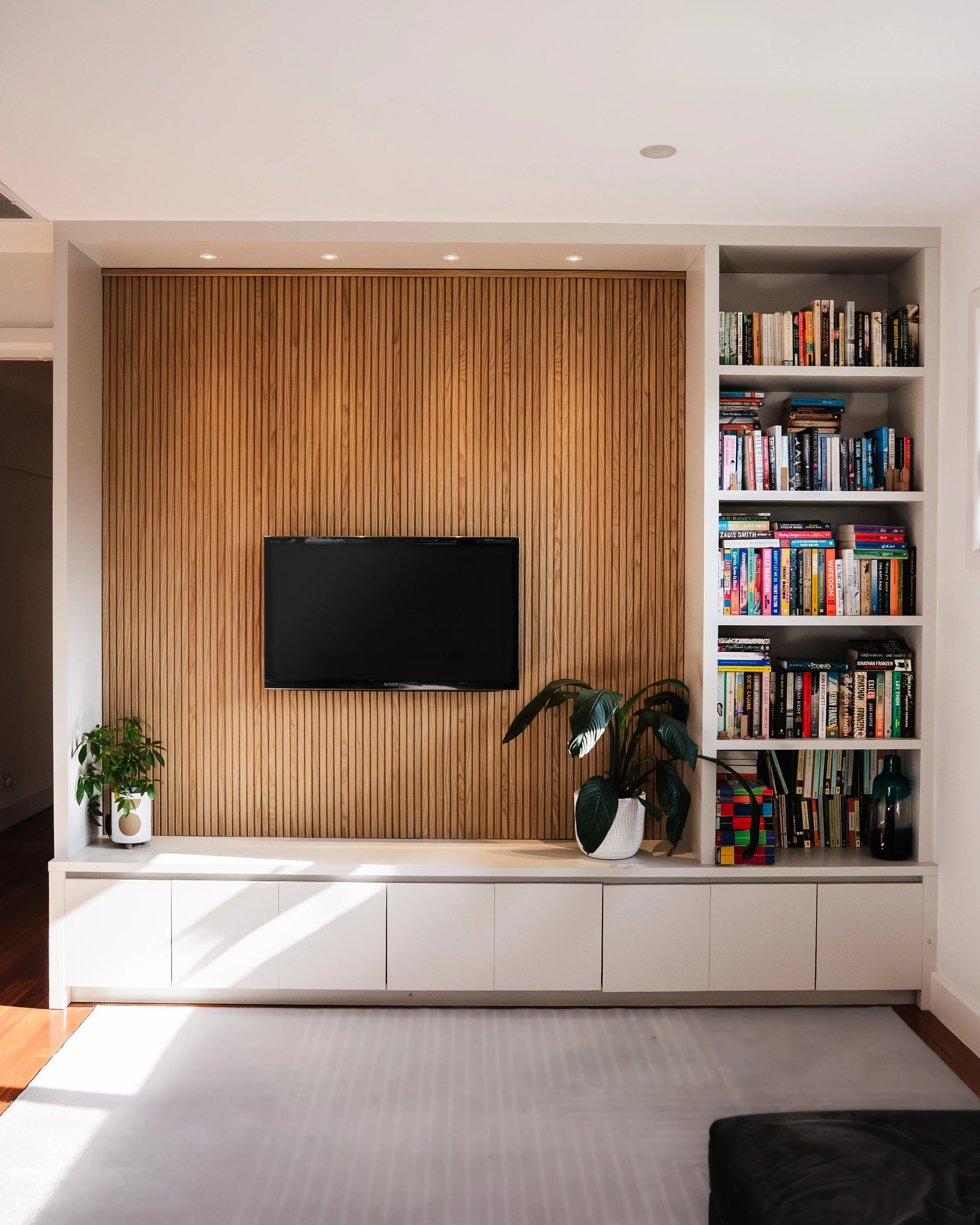 Built-in media unit with ribbed timber TV wall and bookshelf joinery, Yarraville renovation by Lúrae Studio