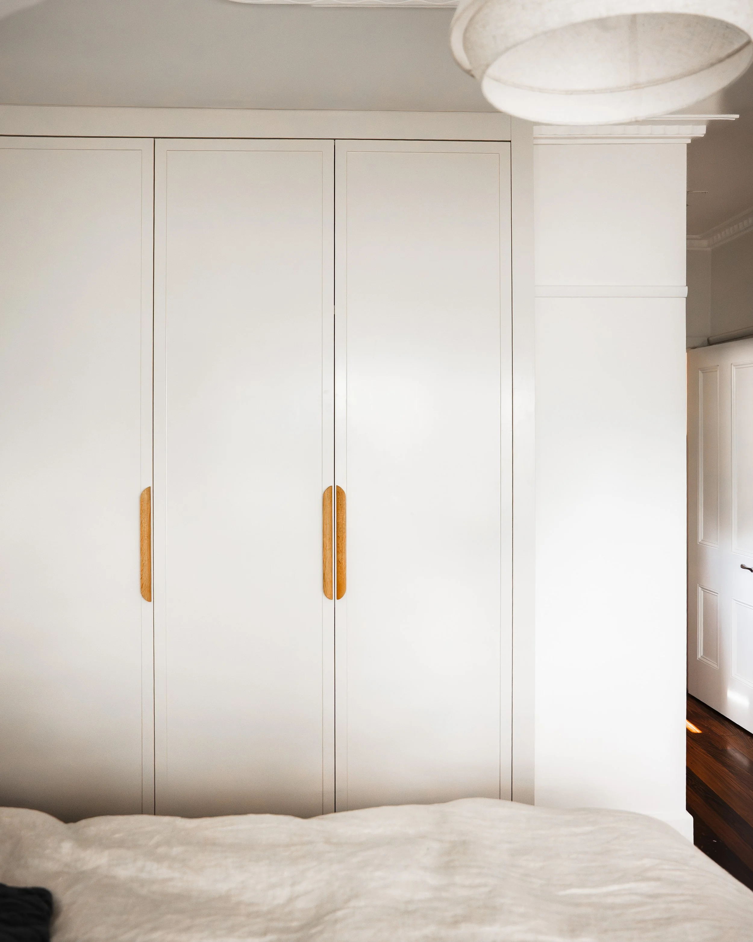 Streamlined three-door wardrobe with timber pull handles, main bedroom, Yarraville renovation by Lúrae Studio