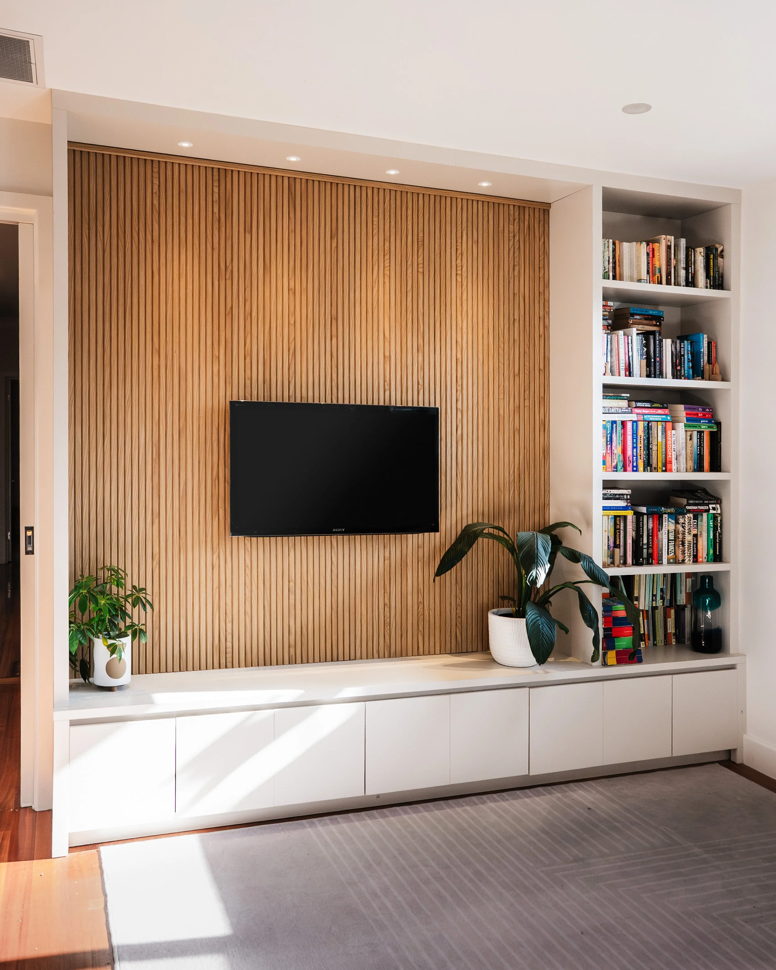 Built-in media unit with ribbed timber TV wall and bookshelf joinery, Yarraville renovation by Lúrae Studio